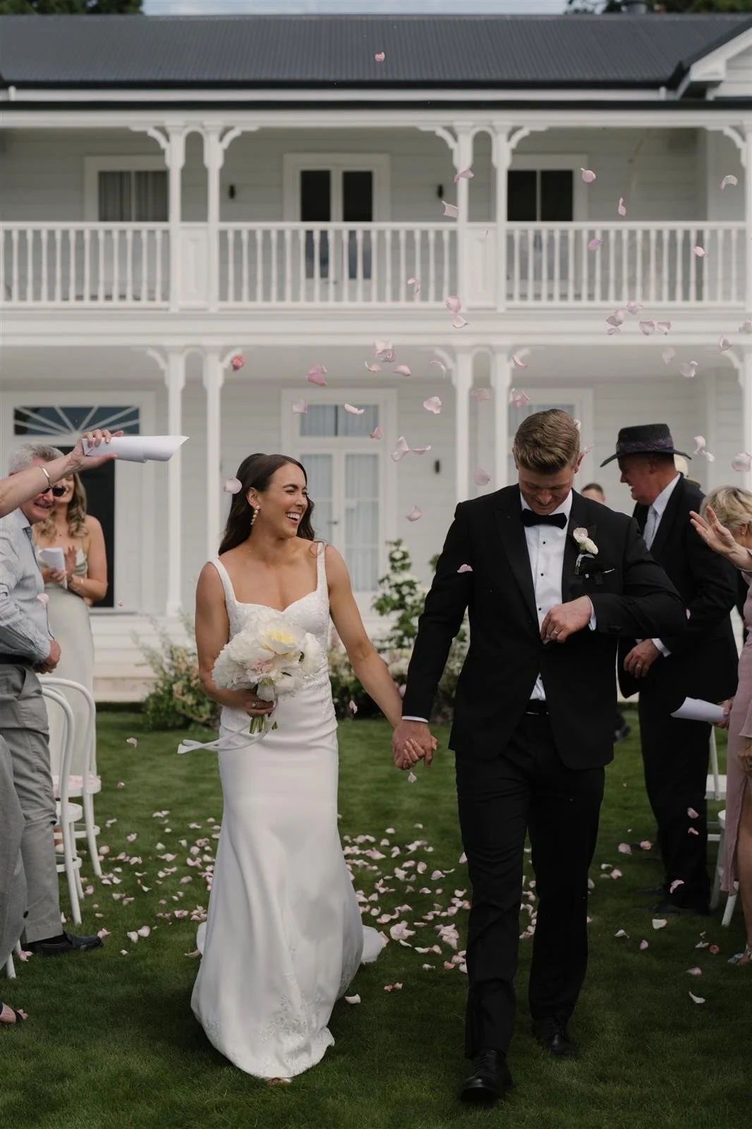 Husband and wife showered in petals walking out of garden ceremony