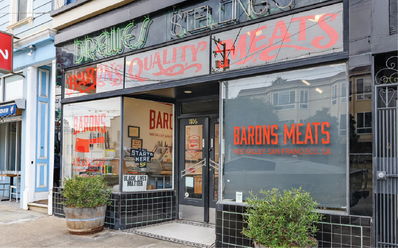 Storefront for Barons Meats in Noe Valley, San Francisco, with signs indicating quality and meats, and a Halloween decoration of a large plastic knife and a Black Lives Matter sign in the window.