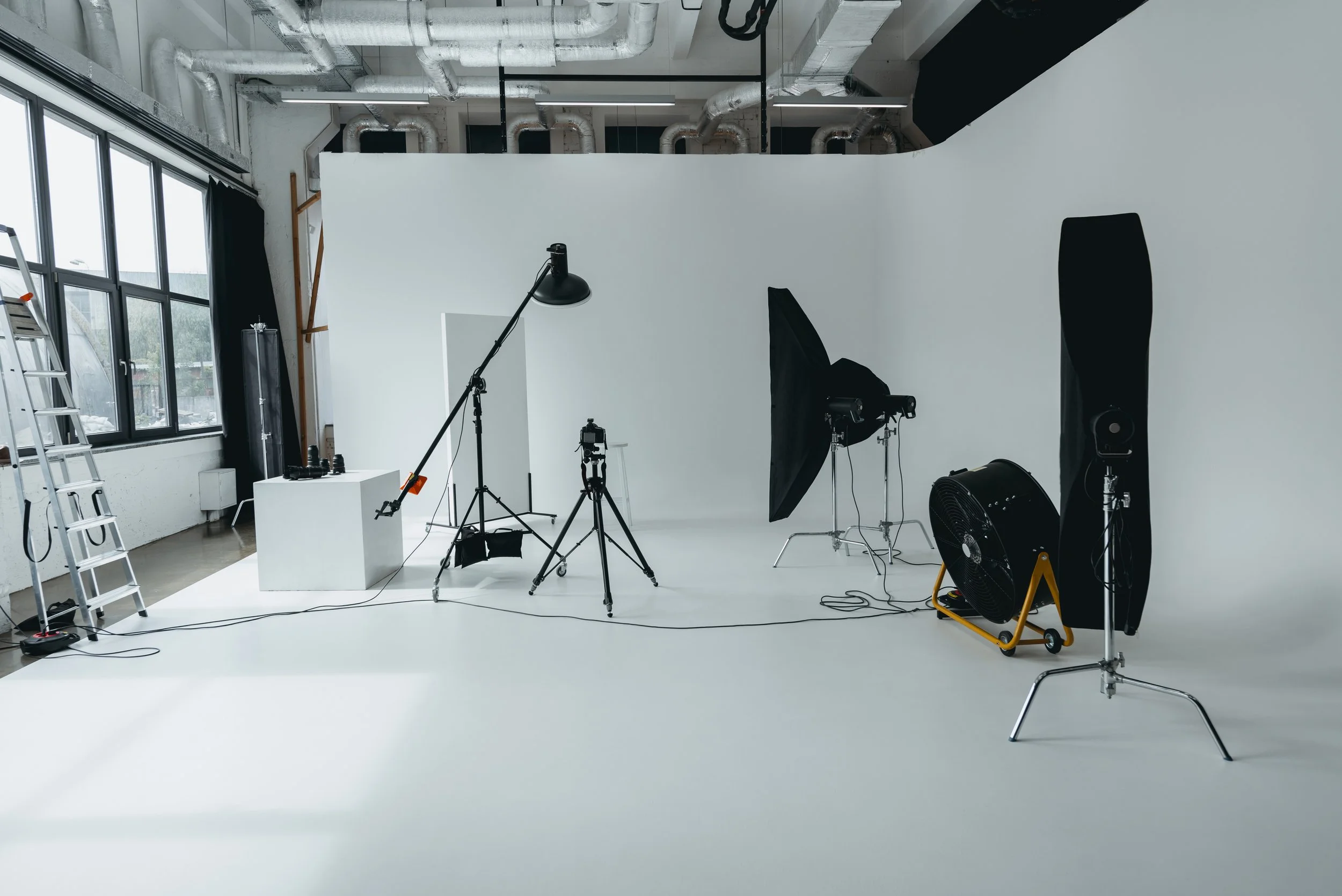 Photography studio with professional lighting, umbrellas, and a white seamless background.