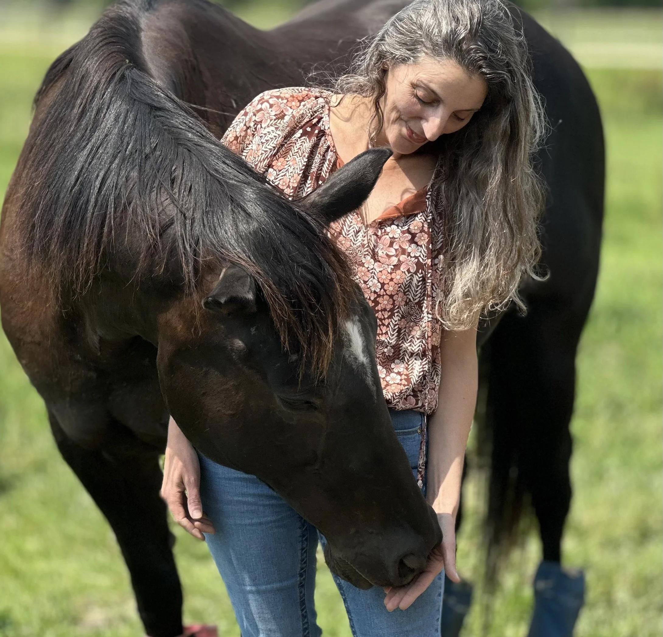 Linda chacholiades standing by horse with her hand out feeding it a treat