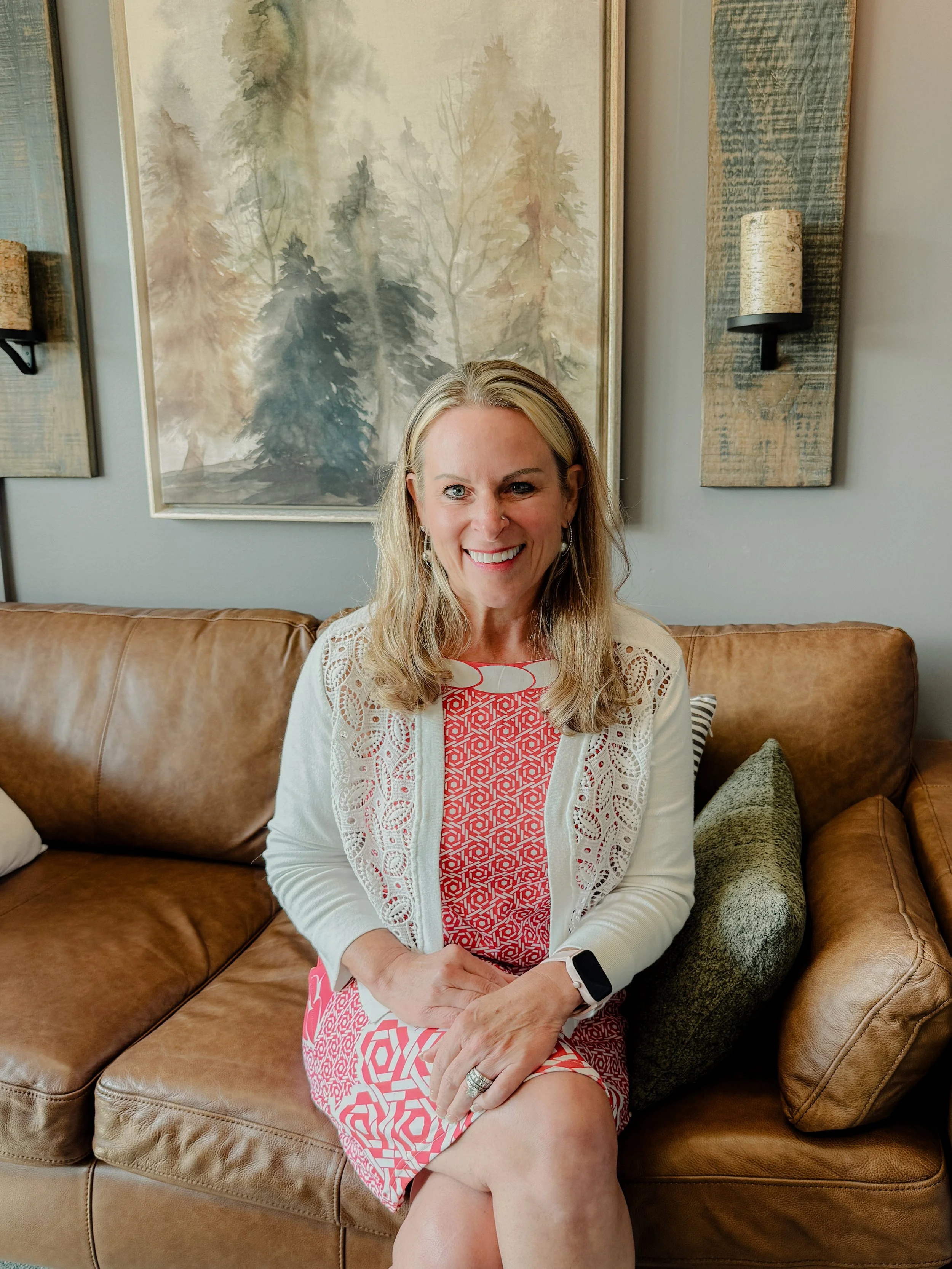 Counselor Darcy Stivland sitting on couch in nature inspired therapy room.