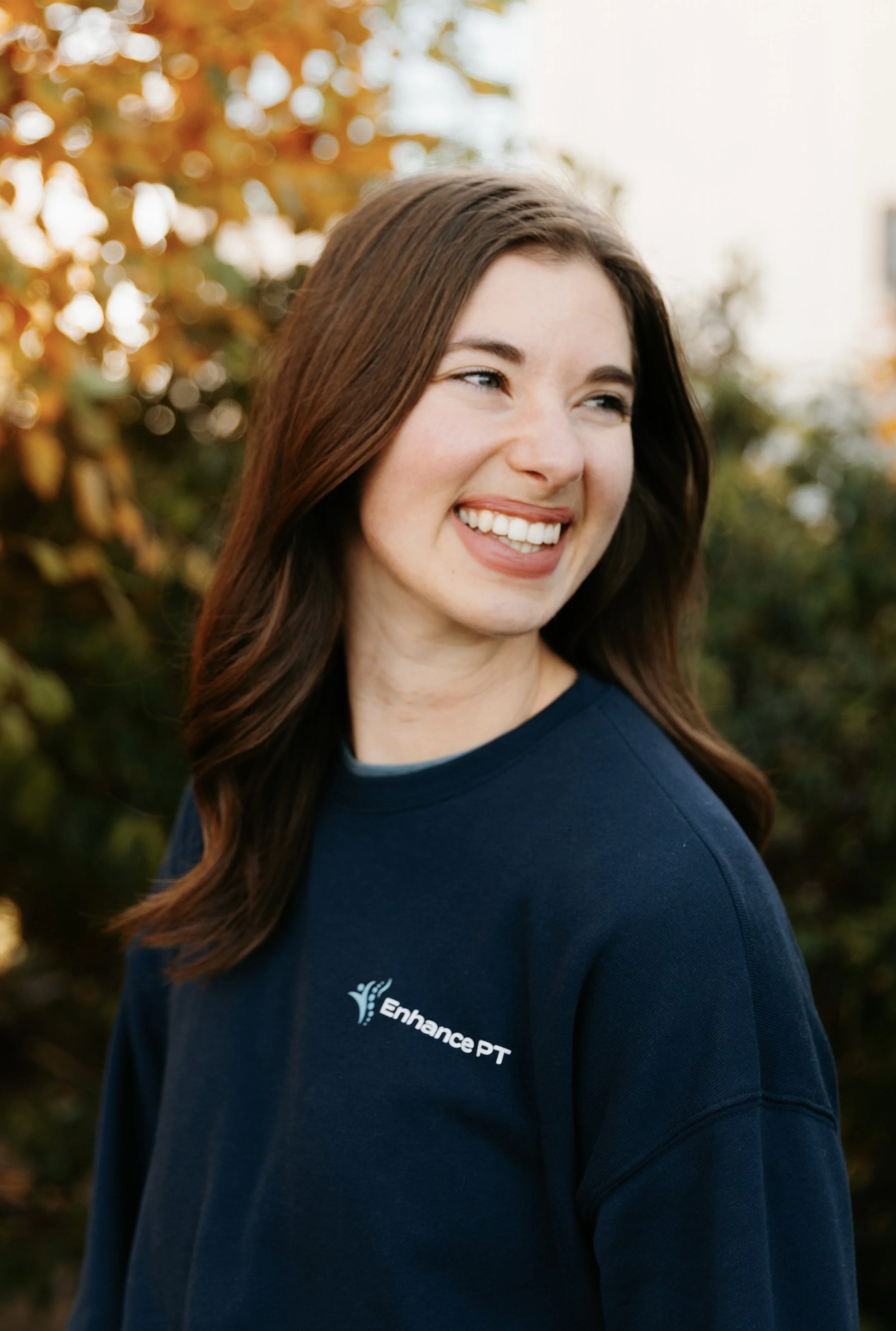 Bethany Reuter looking off in distance smiling in front of trees