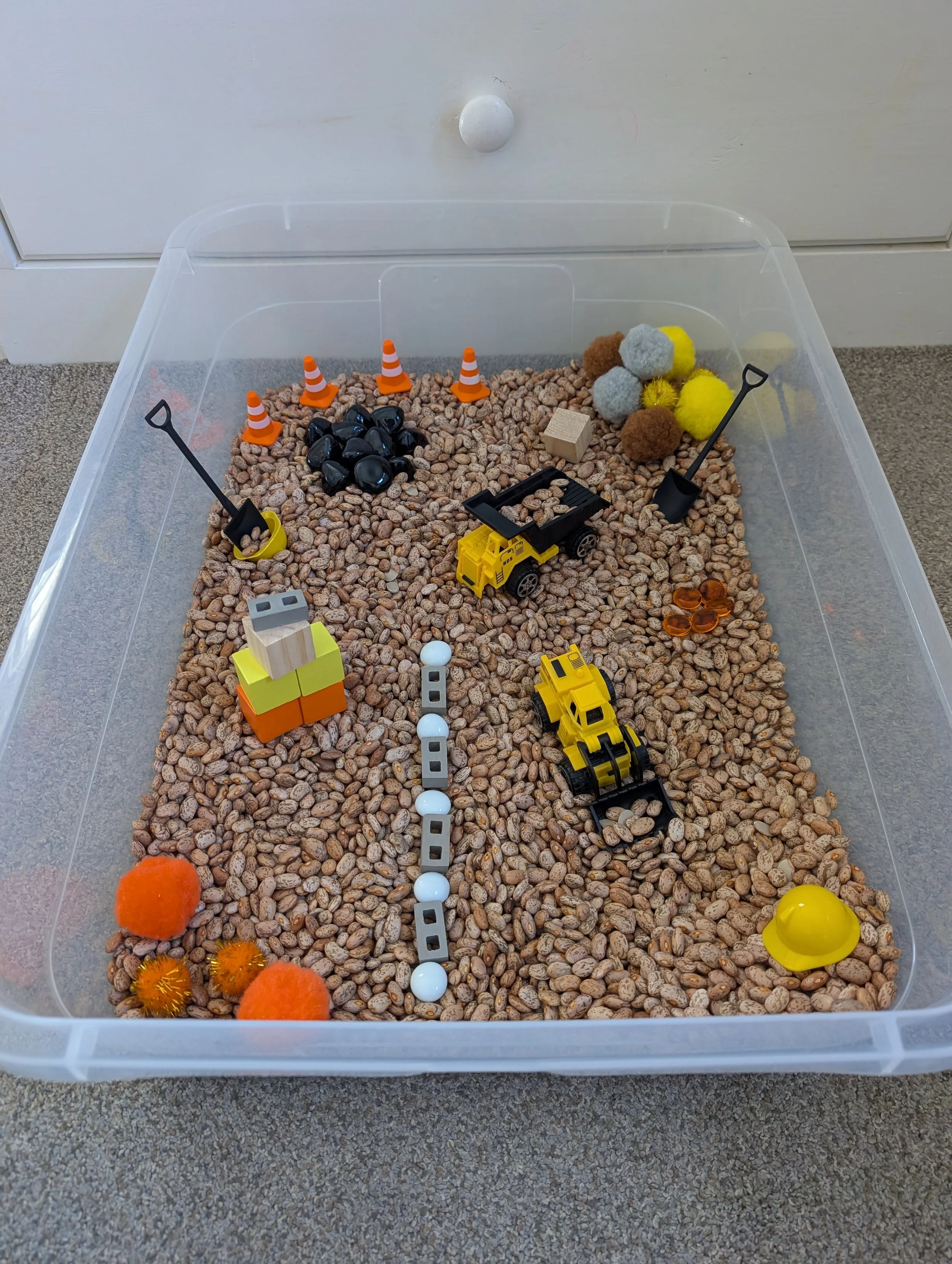 Child's open-ended play with Play Sparks Construction Spark Box loose parts arranged in a sensory bin filled with dried beans - imaginative construction sensory play for boys and girls ages 4 to 8