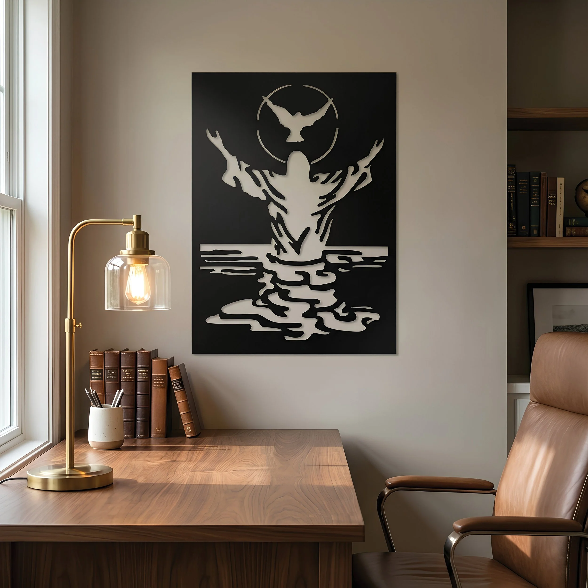 Black metal wall art of the Baptism of Christ as he rises from the water a dove flying above his head, displayed above a wooden desk in a softly lit office.