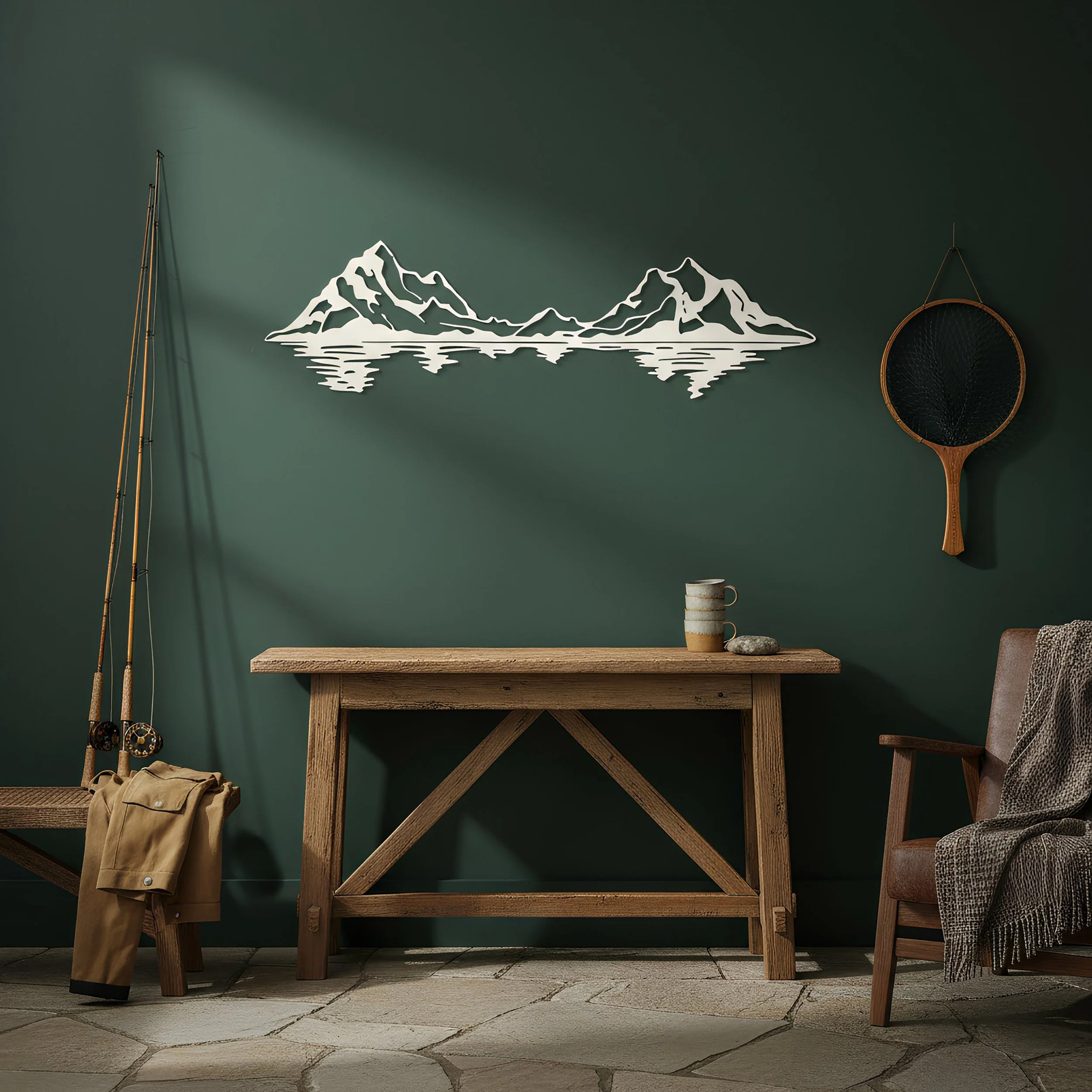 White metal wall art of a mountain range with water reflection, displayed above a wooden console table in a rustic room with fishing decor.