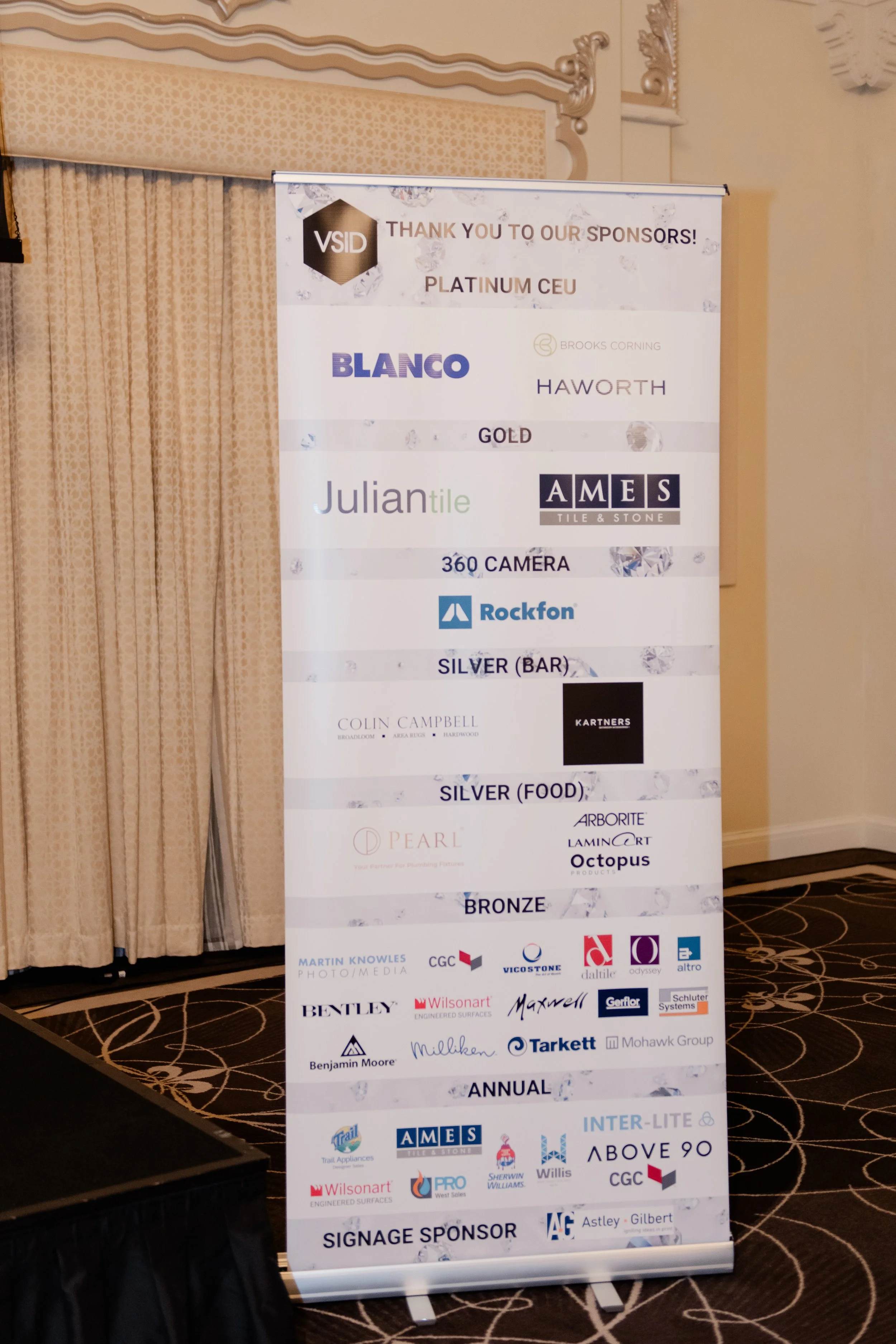 A vertical banner displaying sponsor logos and acknowledgments at a corporate event.