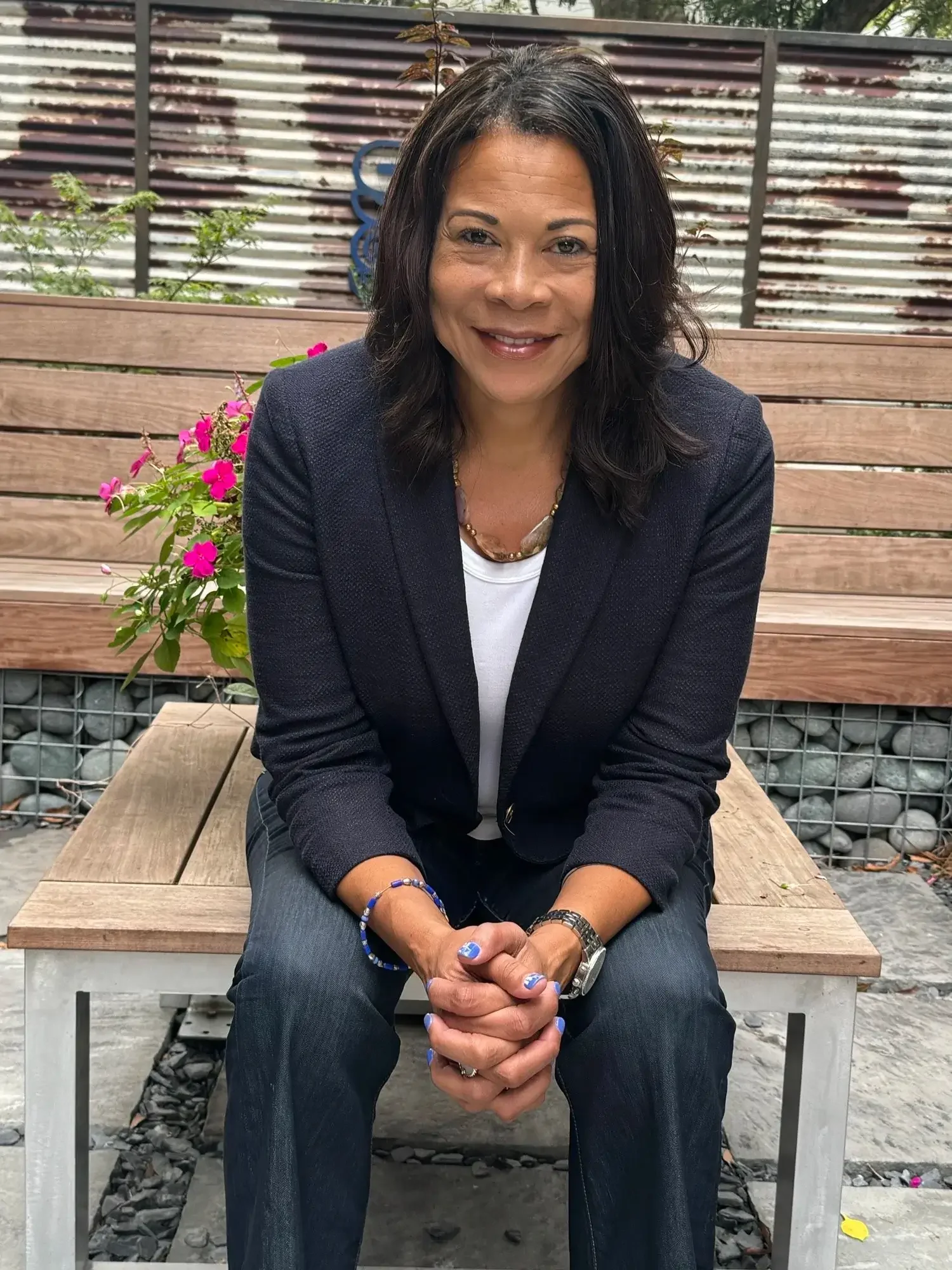 Professional woman smiling at the camera while working in a modern office environment with collaborative and creative atmosphere.