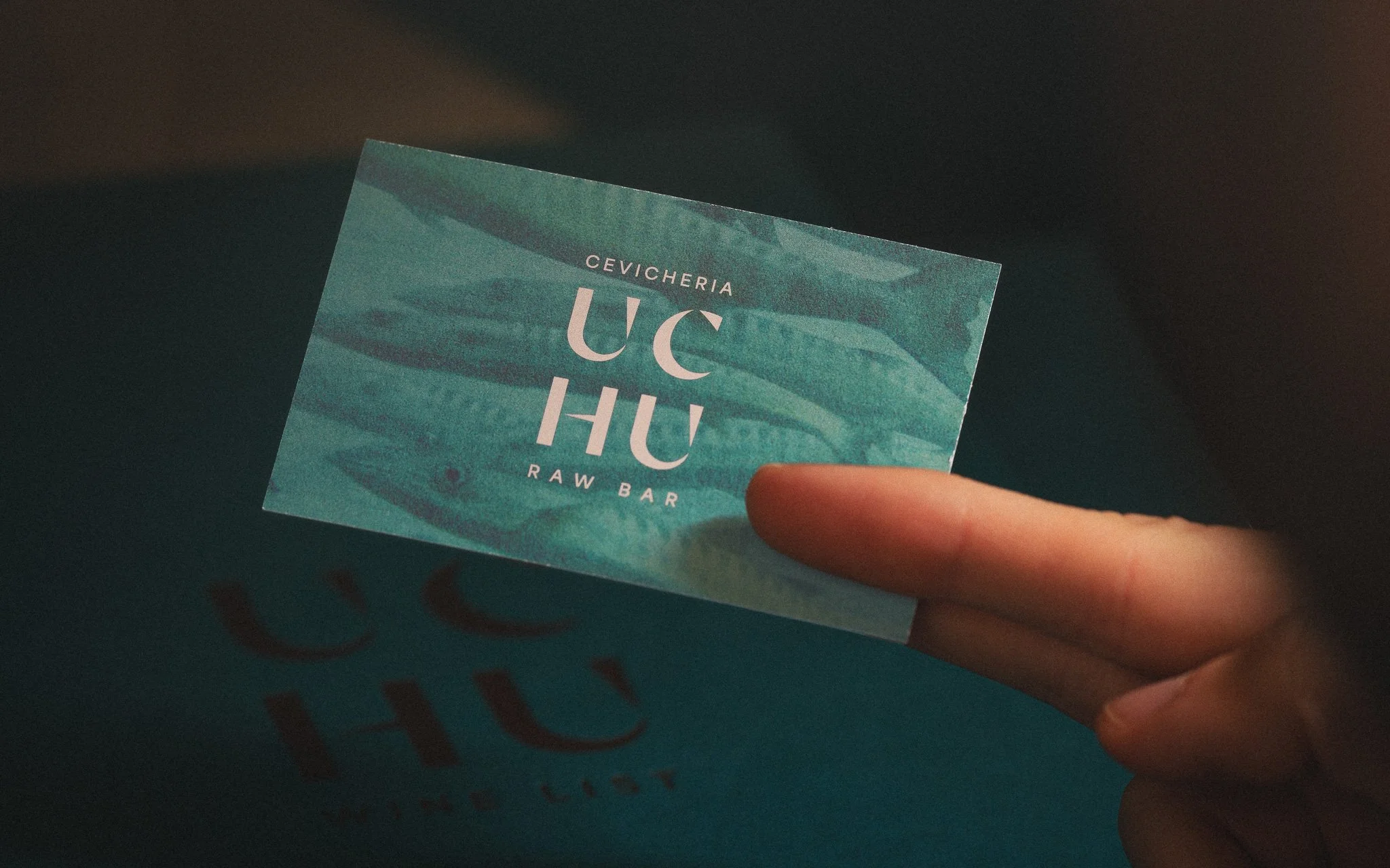 A person holding a teal UCHU restaurant giftcard.