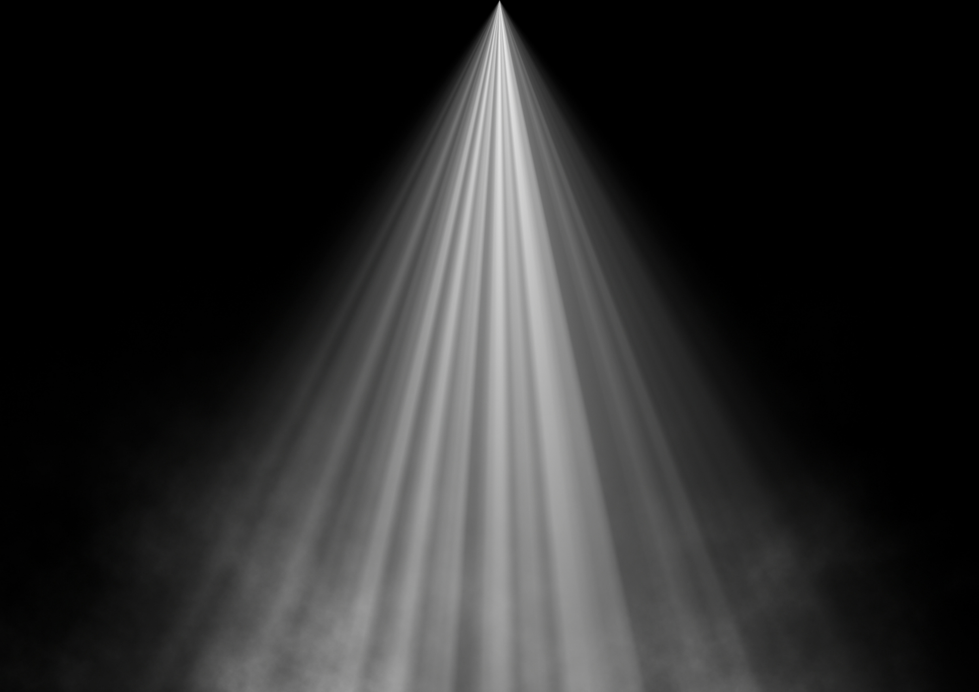 A spotlight shining down through a black background, creating a cone-shaped beam of light.