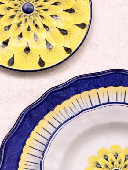 Stratificata hand-painted Italian ceramic plates in blue and yellow floral pattern on linen background