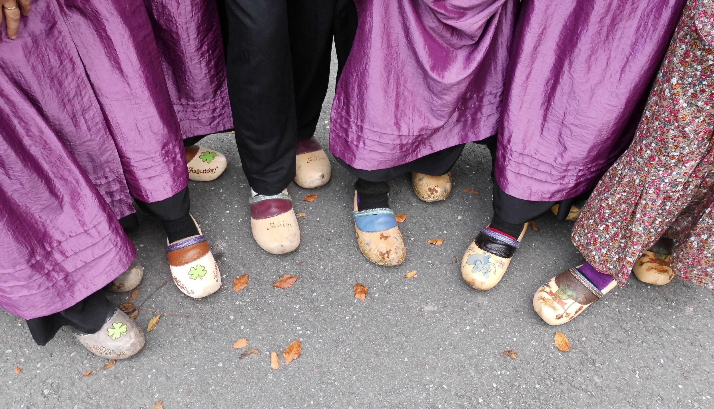 Menschen tragen traditionelle Kleidung und Schuhe aus Holz bei einer kulturellen Veranstaltung.
