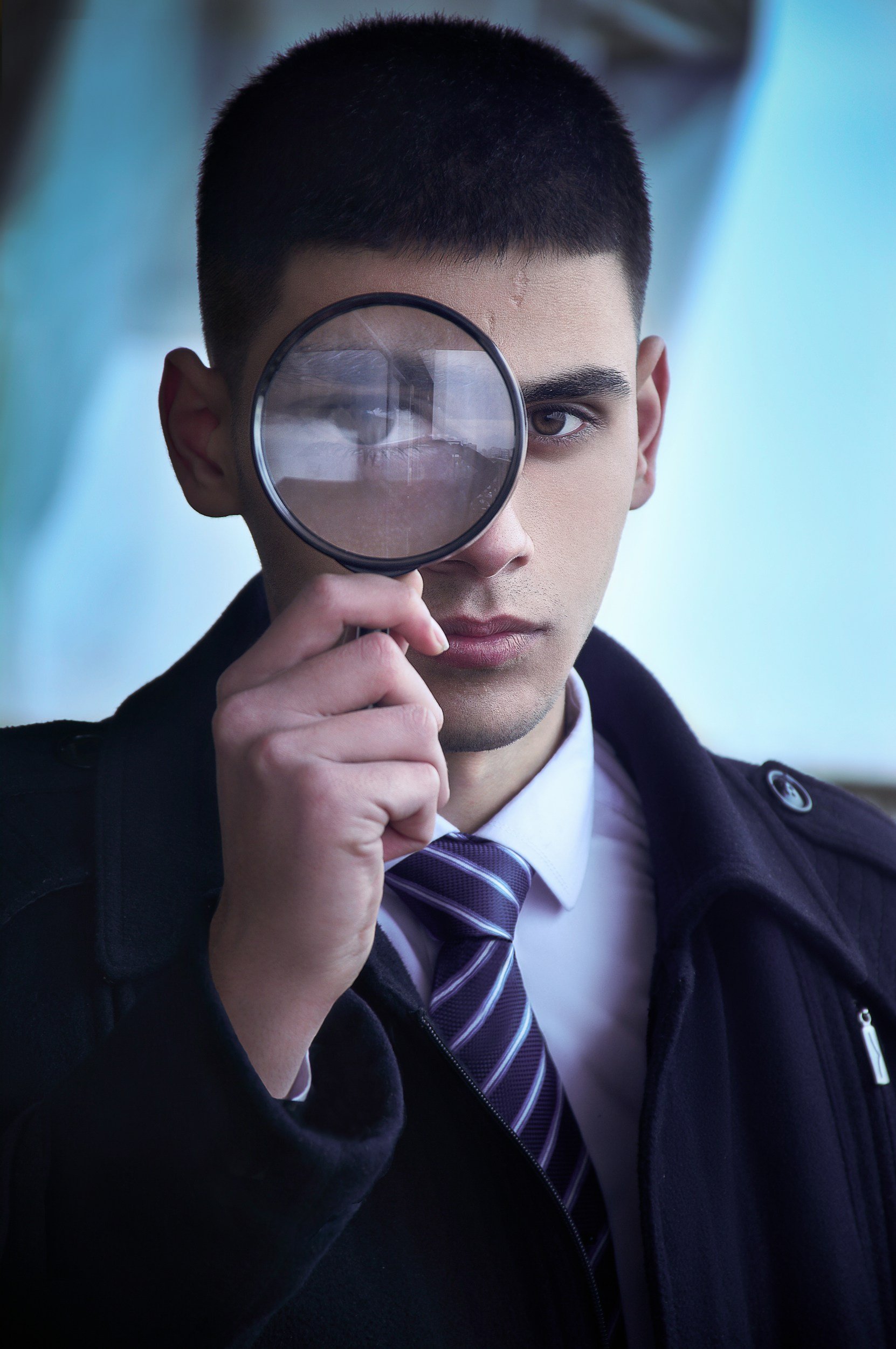 Young man with magnifying glass over eye – Careful financial review and insurance policy analysis for veterans or families.