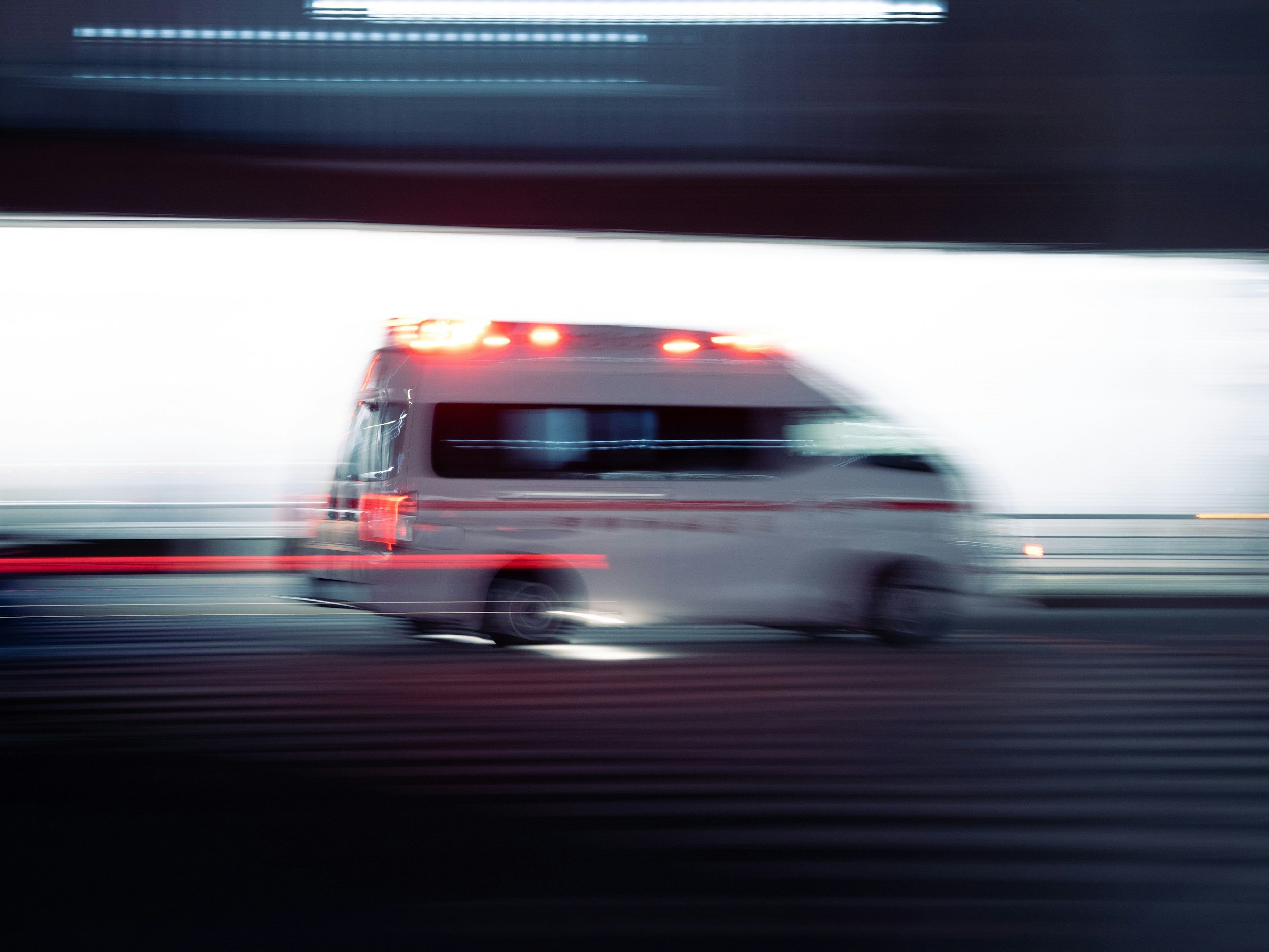 Blurred mobile police van moving on highway with red and blue lights on at night.