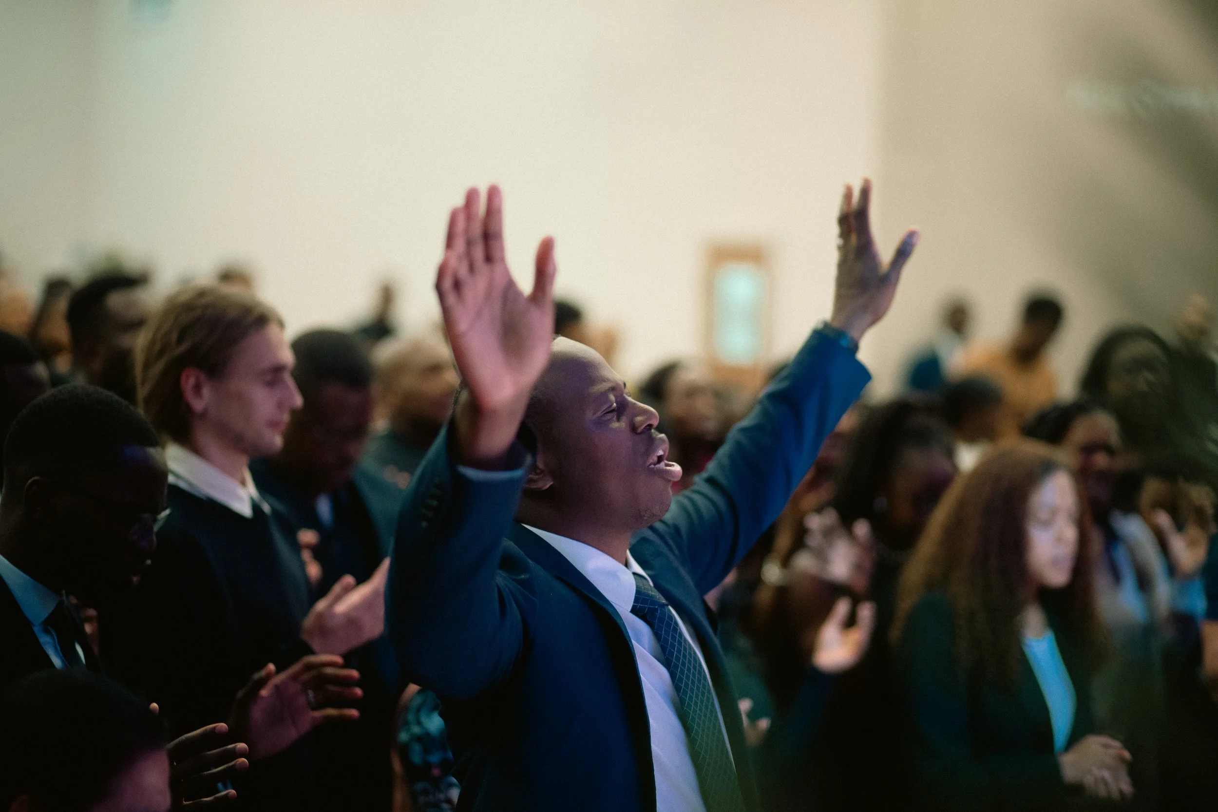 A diverse group of people seated in an audience, with some raising their hands during a presentation or conference.