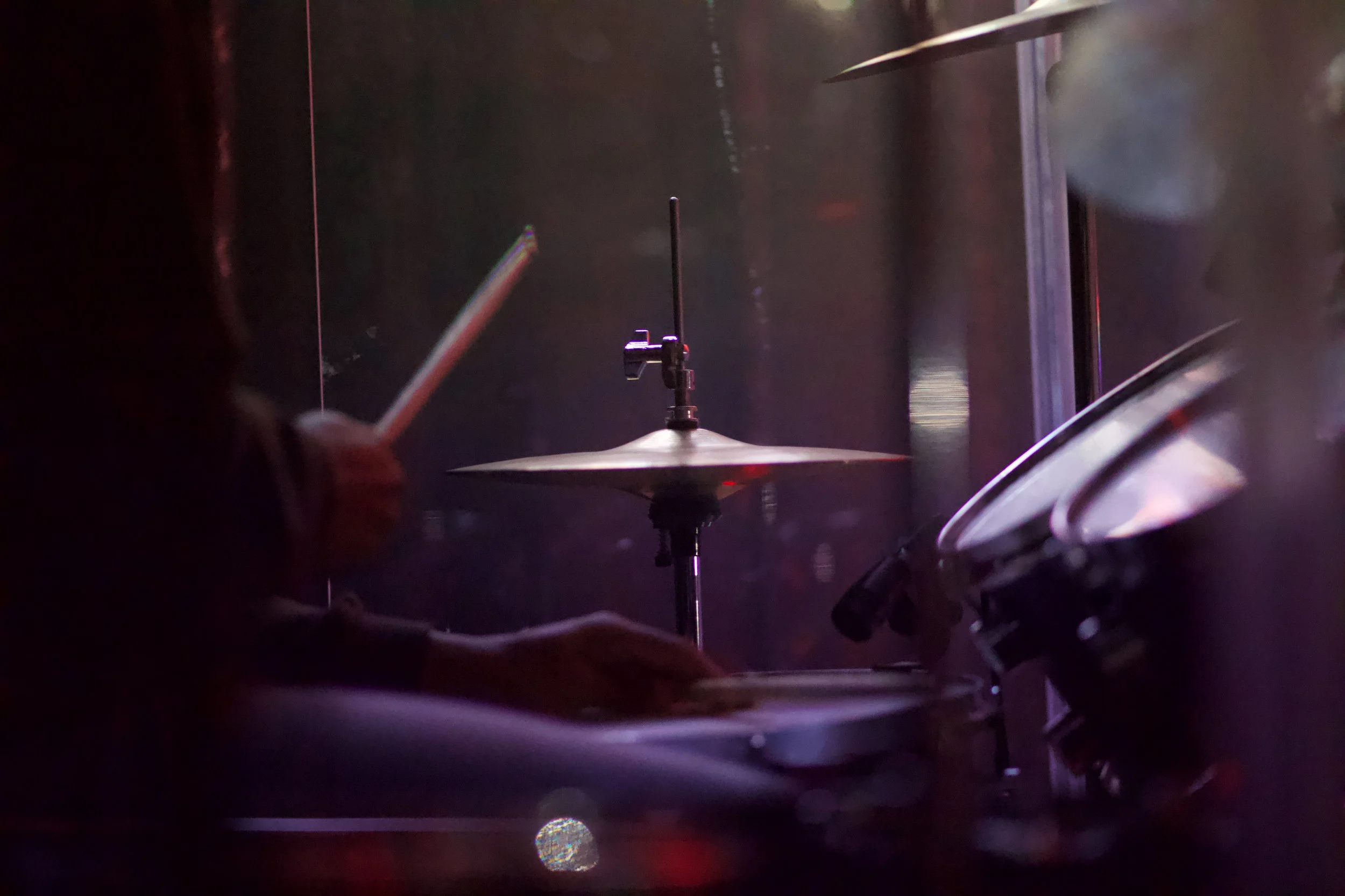 Close-up of a drum set with a cymbal and a drumstick in a dark setting.