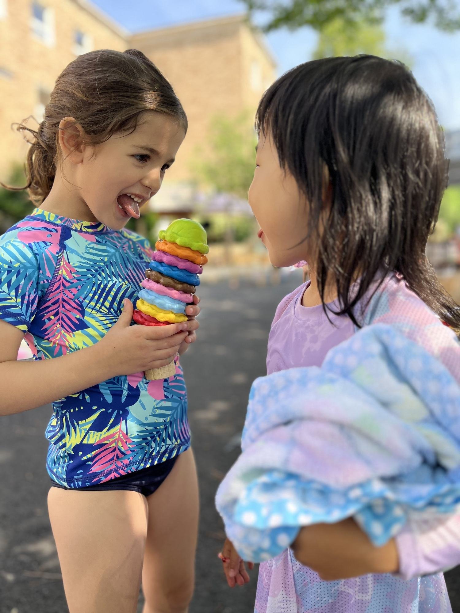 two friends sharing a toy ice cream cone in swimsuits