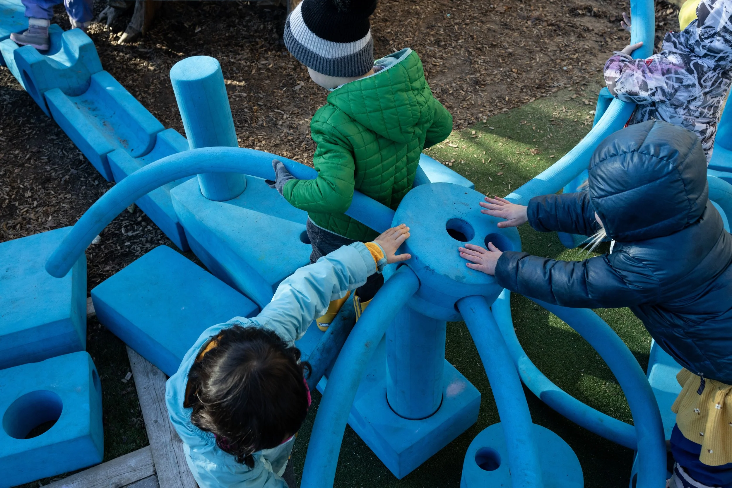 Children playing on a blue playground structure outdoors.