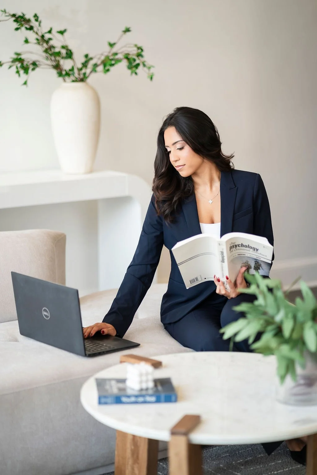 Keystone Research Assistant, Kristen, sitting on a couch working on her laptop and an opened psychology textbook