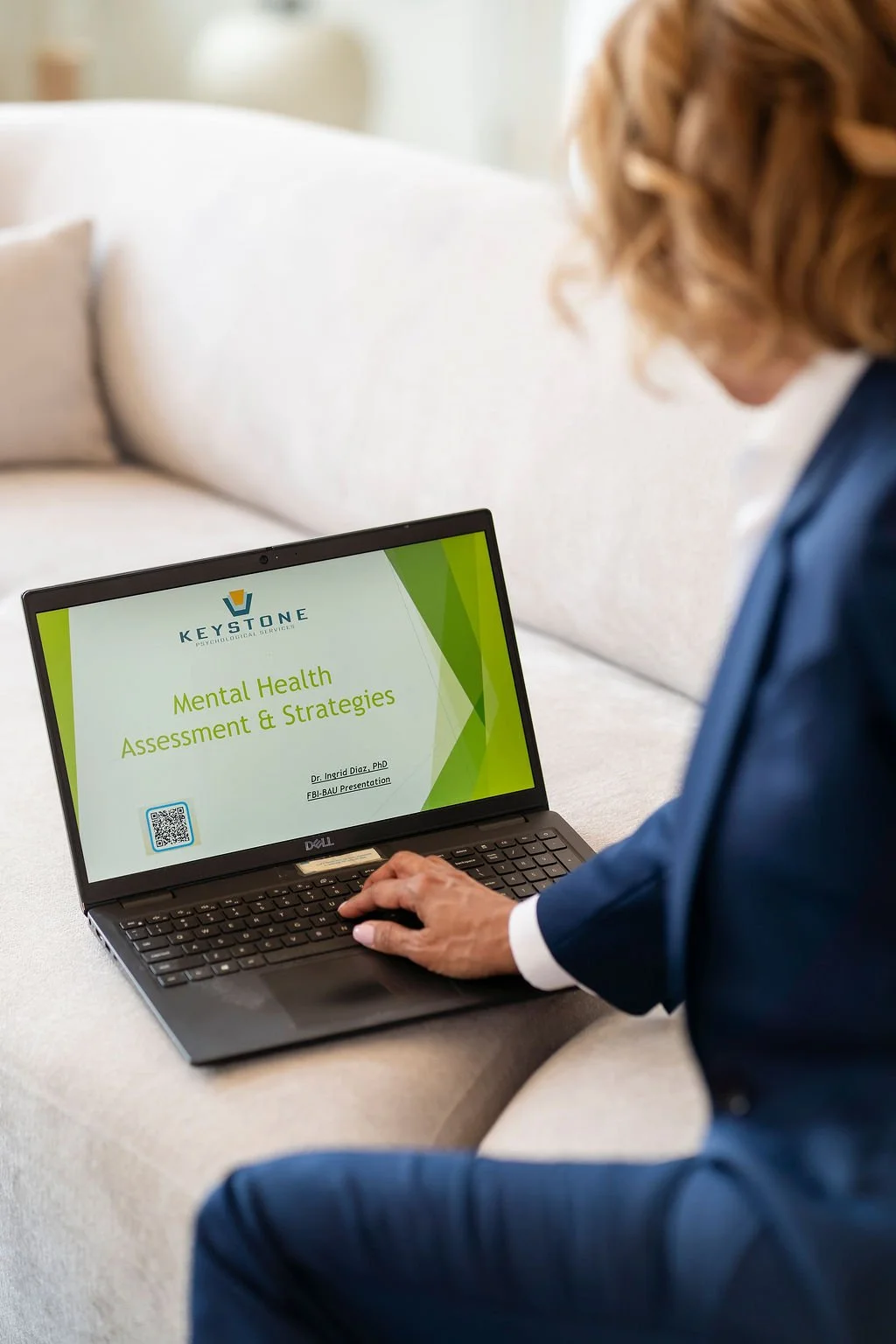 Dr. Diaz framed from behind her left shoulder, looking at laptop content of "Keystone Mental Health Assessment & Strategies