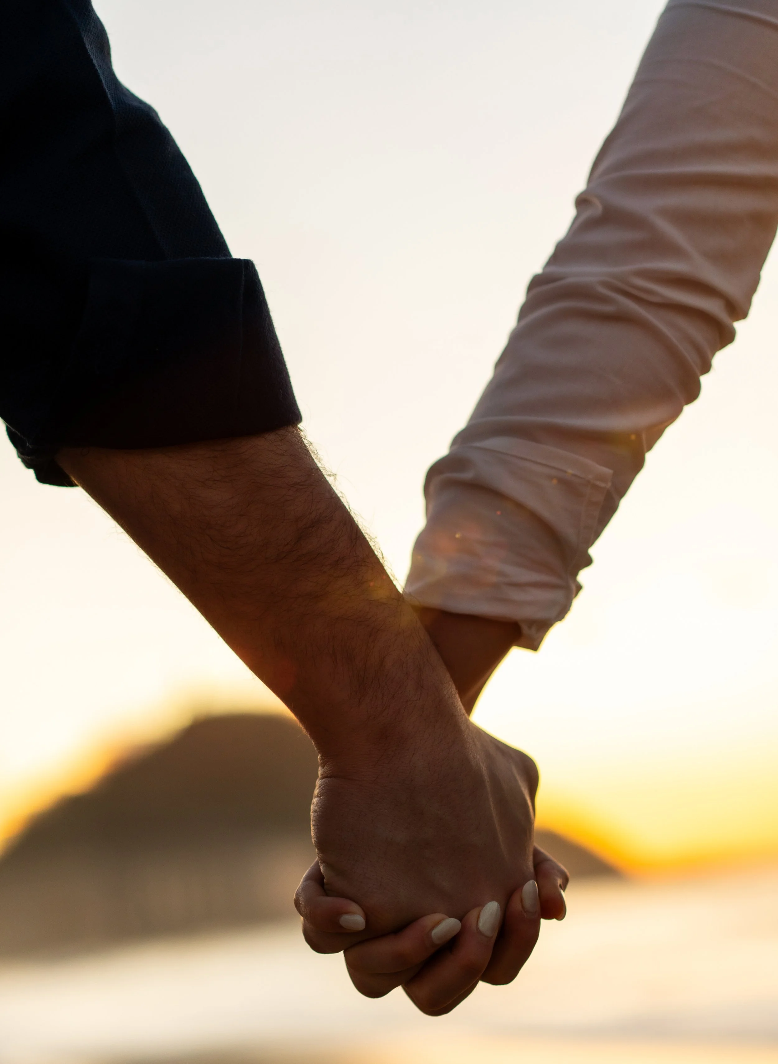 Close-up of two people holding hands during sunset through therapy with Mary Evelyn Moore for Couples