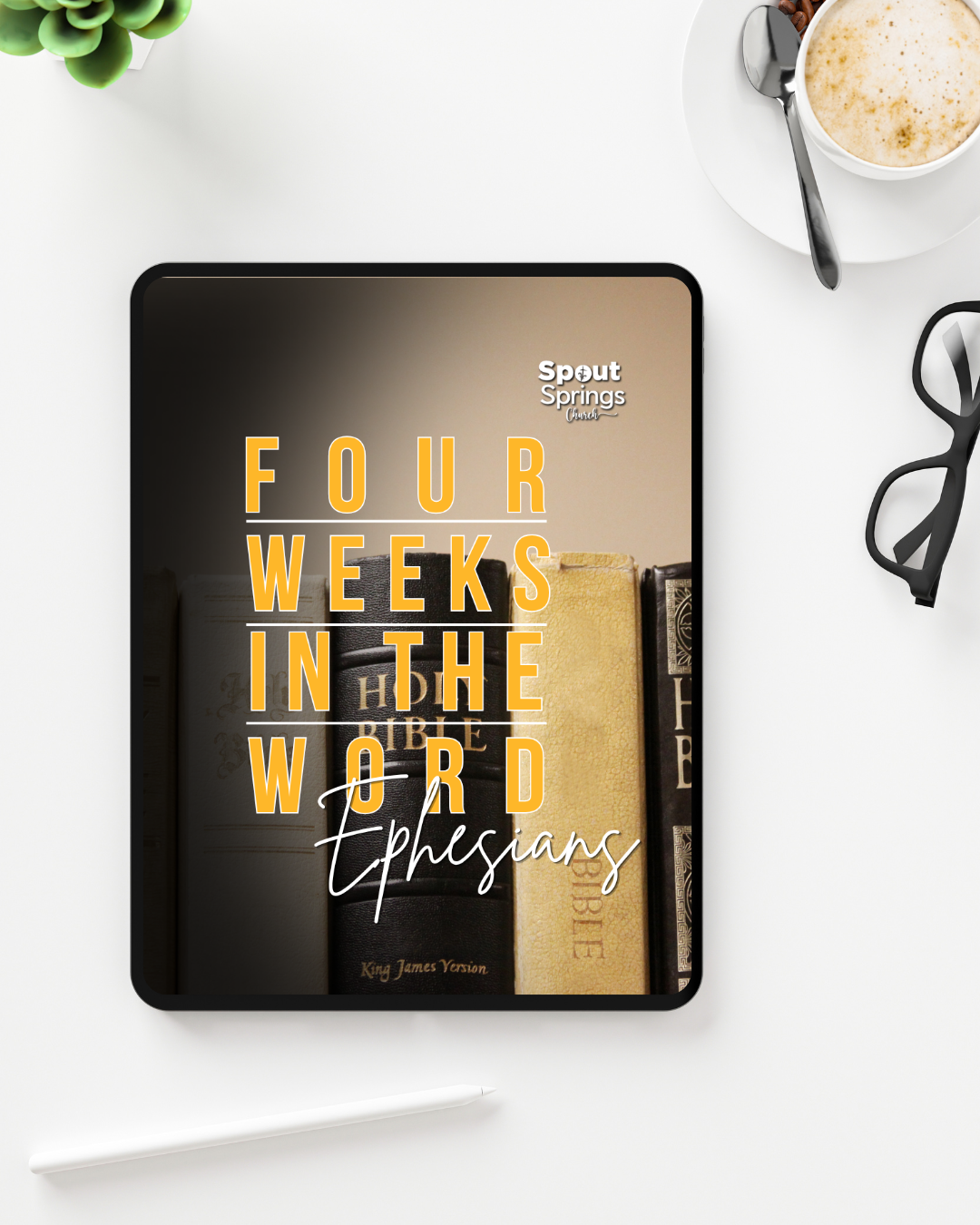 Electronic tablet displaying the book cover 'Four Weeks in the Word: Ephesians' by Spout Springs Church, surrounded by a cup of coffee, glasses, a potted plant, and a stylus on a white desk.