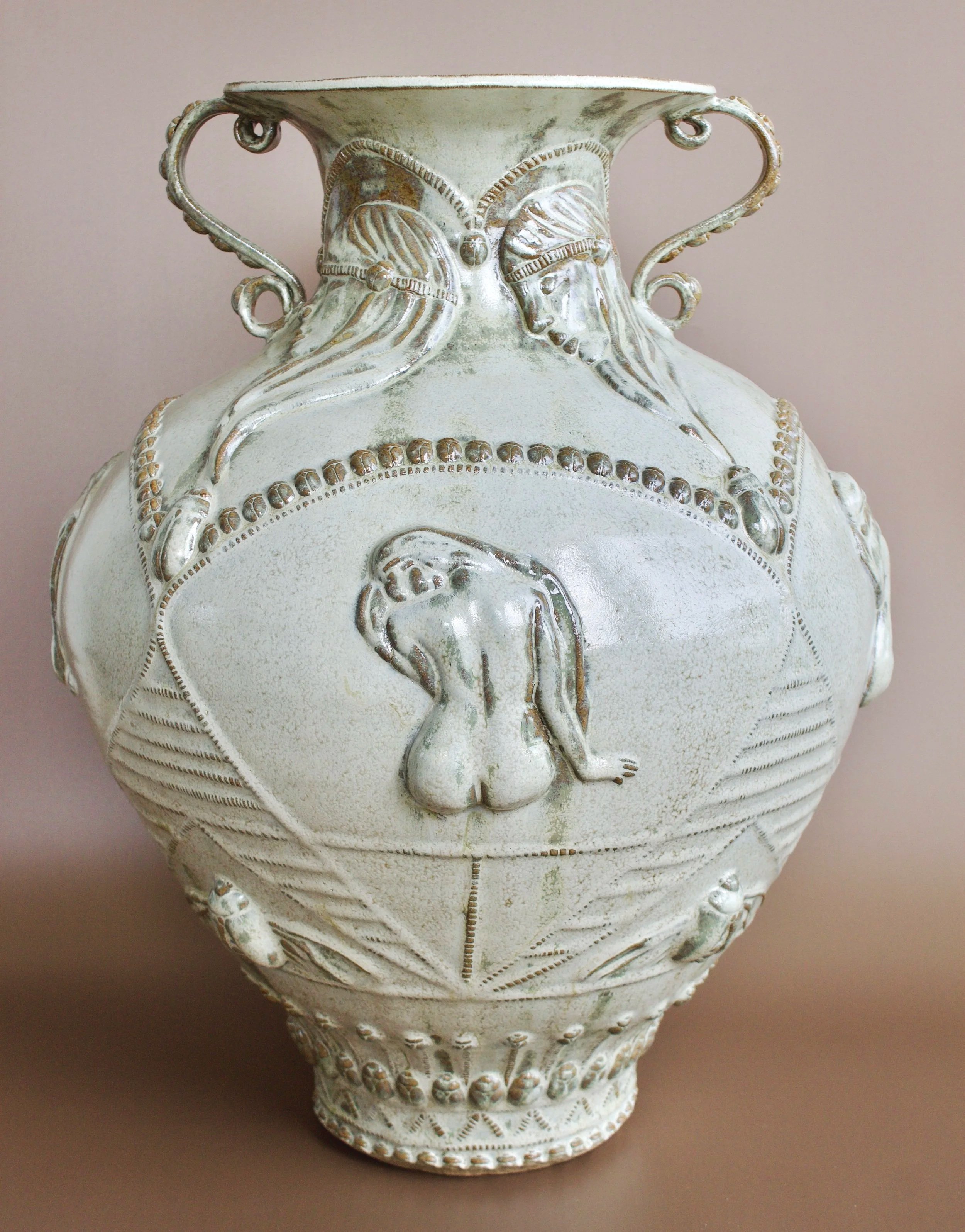 Decorative ceramic vase with relief sculptures of women and a nude woman in the center.