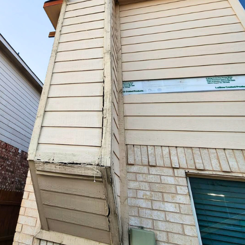Exterior view of a house showing vinyl siding, a brick section, and a window with closed blinds.