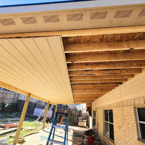 Under construction of a house with new wooden ceiling and exposed beams, with construction tools and materials on the ground.