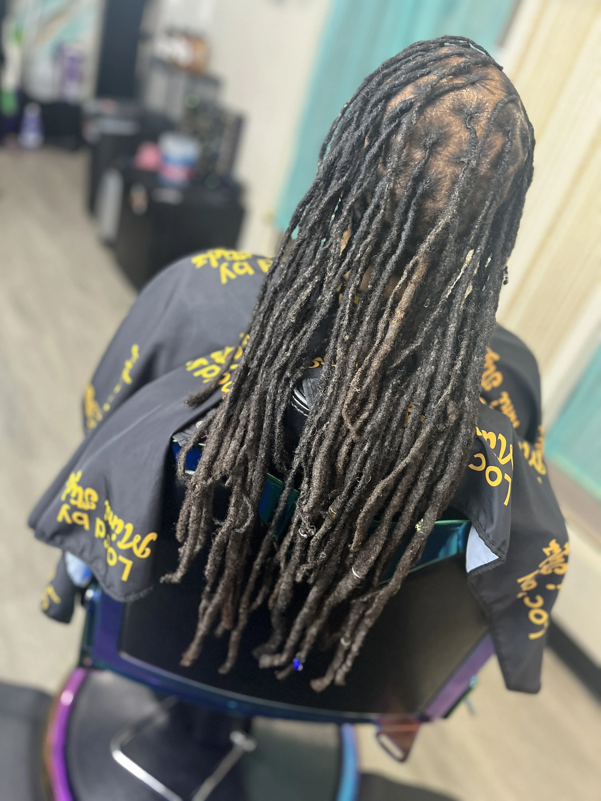 A person with long locs who has experienced the Signature Loc Renewal at The Thairapy Suite
