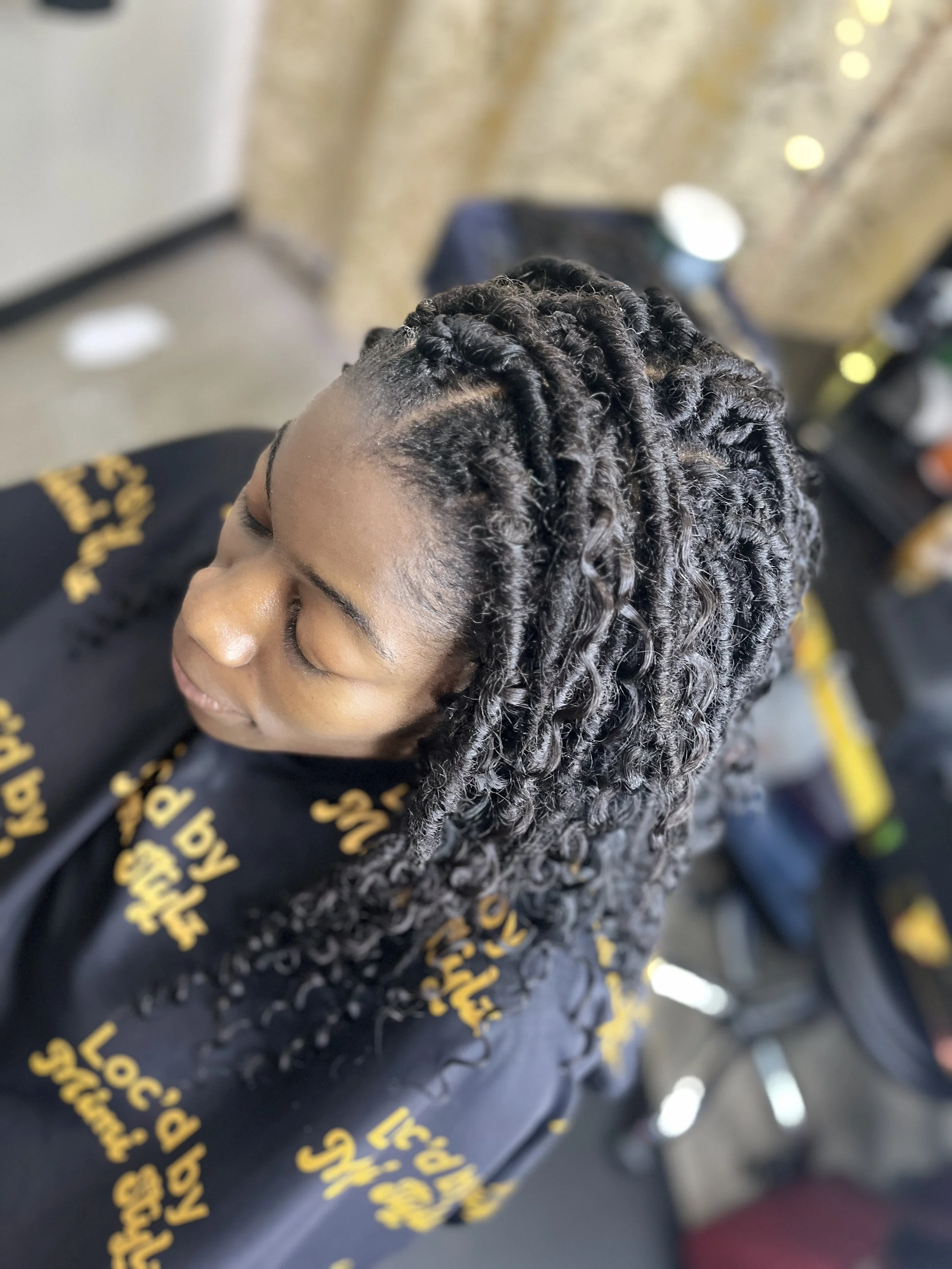 Close-up of a woman with styled, twisted hair getting a haircut in a salon.