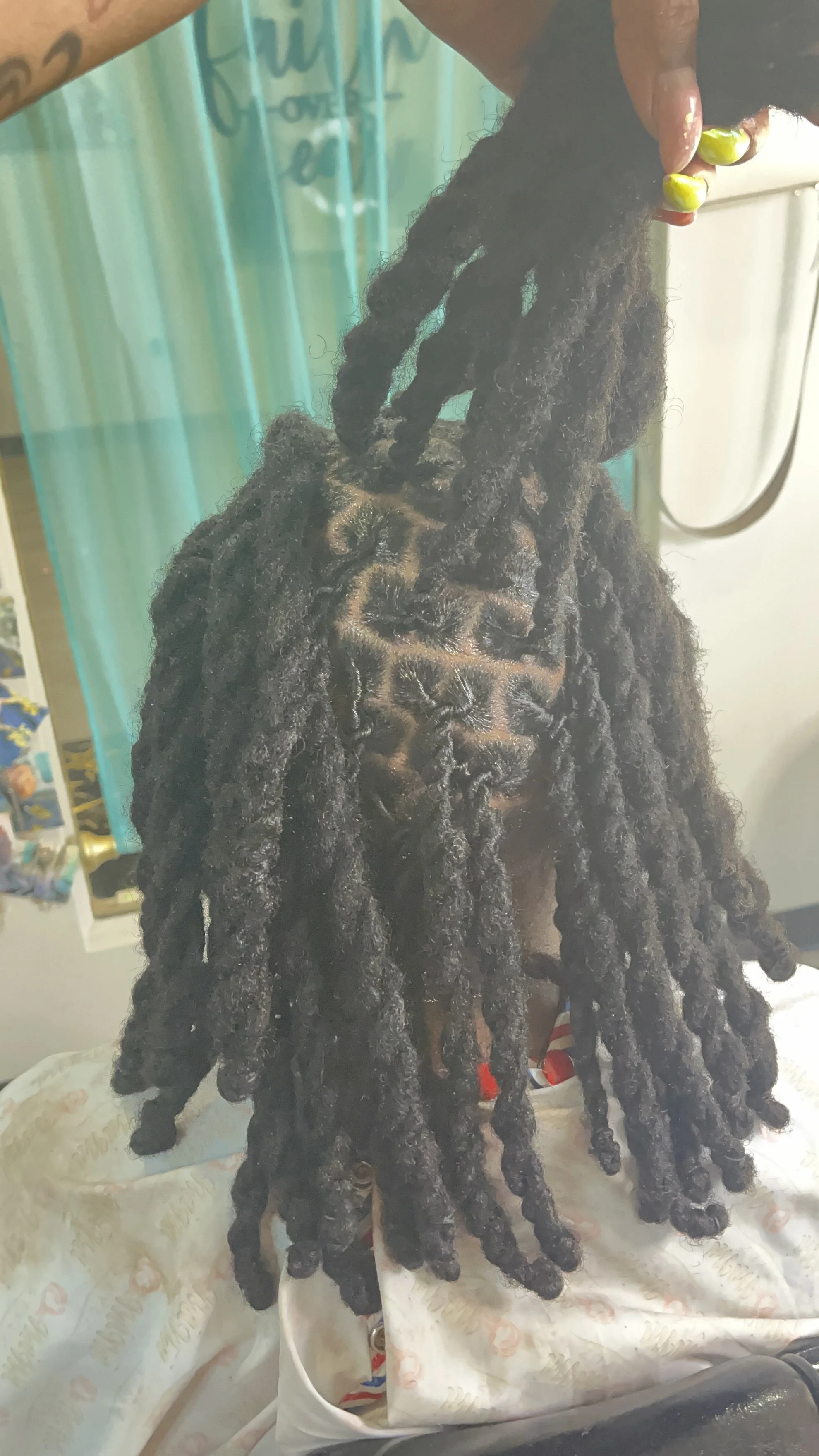 Person holding long, thick dreadlocks with face partially visible in the background.