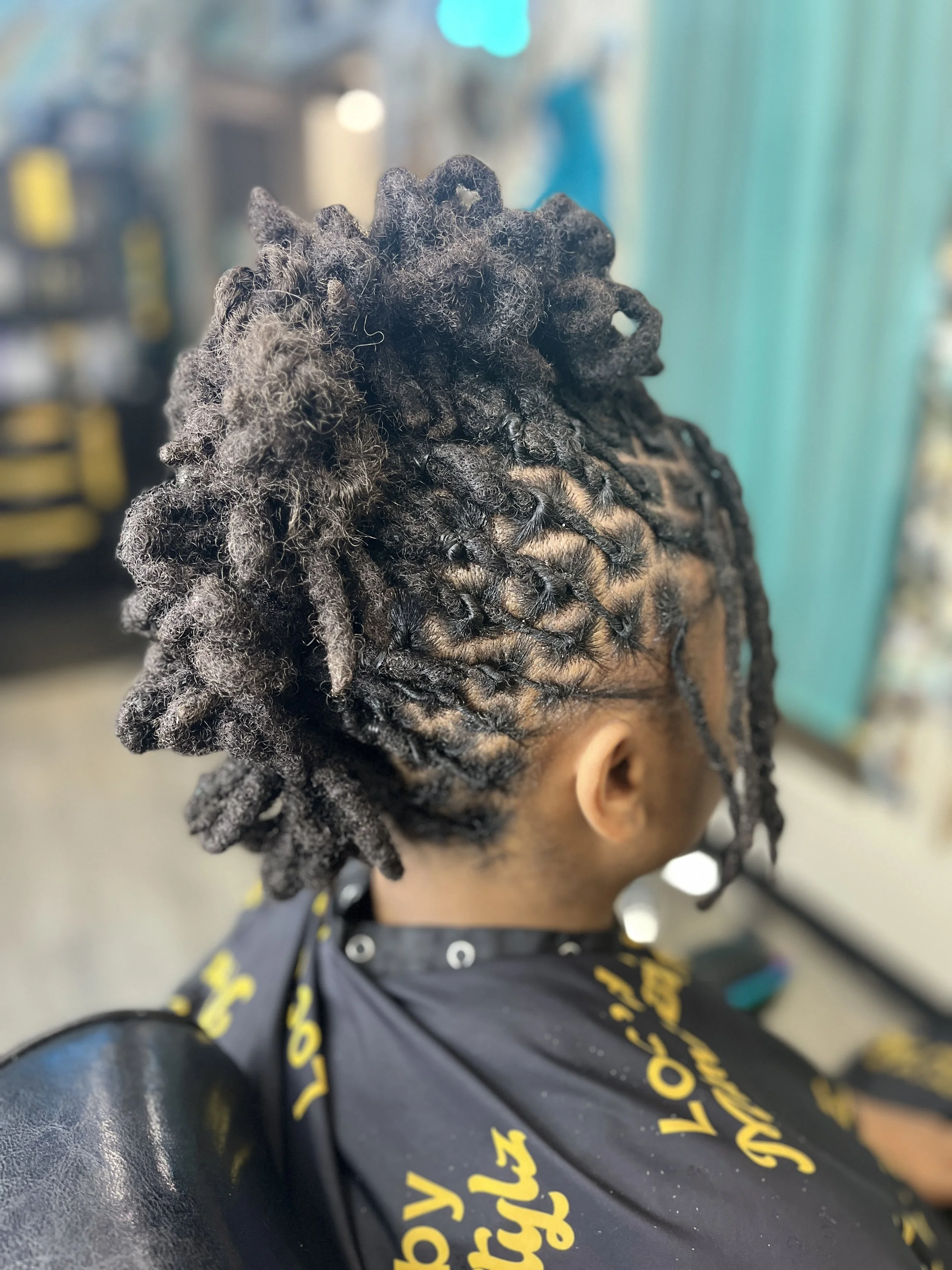 Close-up view of a person's head showcasing neatly styled black dreadlocks.