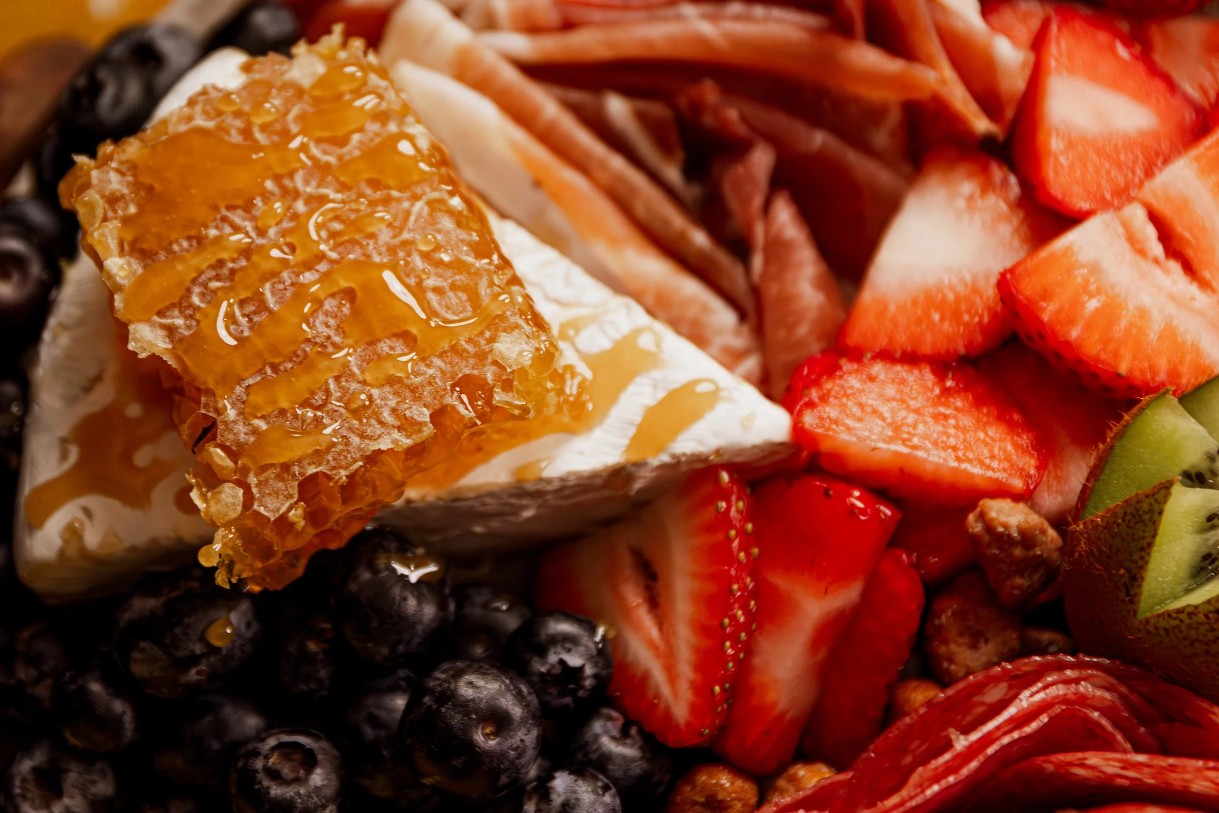 Charcuterie board with cheeses, meats, grapes, olives, pickles, and bread.