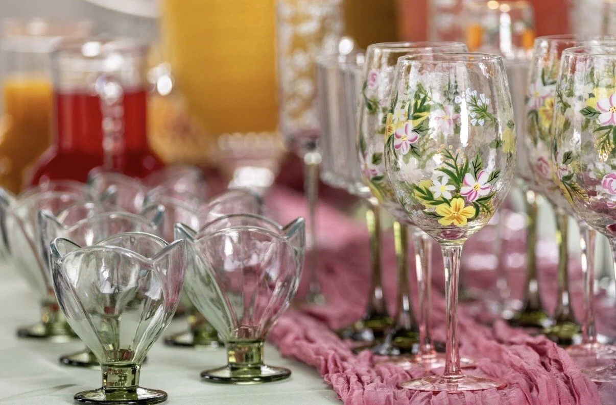 A bar with liquor bottles, wine glasses hanging upside down, and bartending supplies on a marble countertop in a restaurant or bar setting.