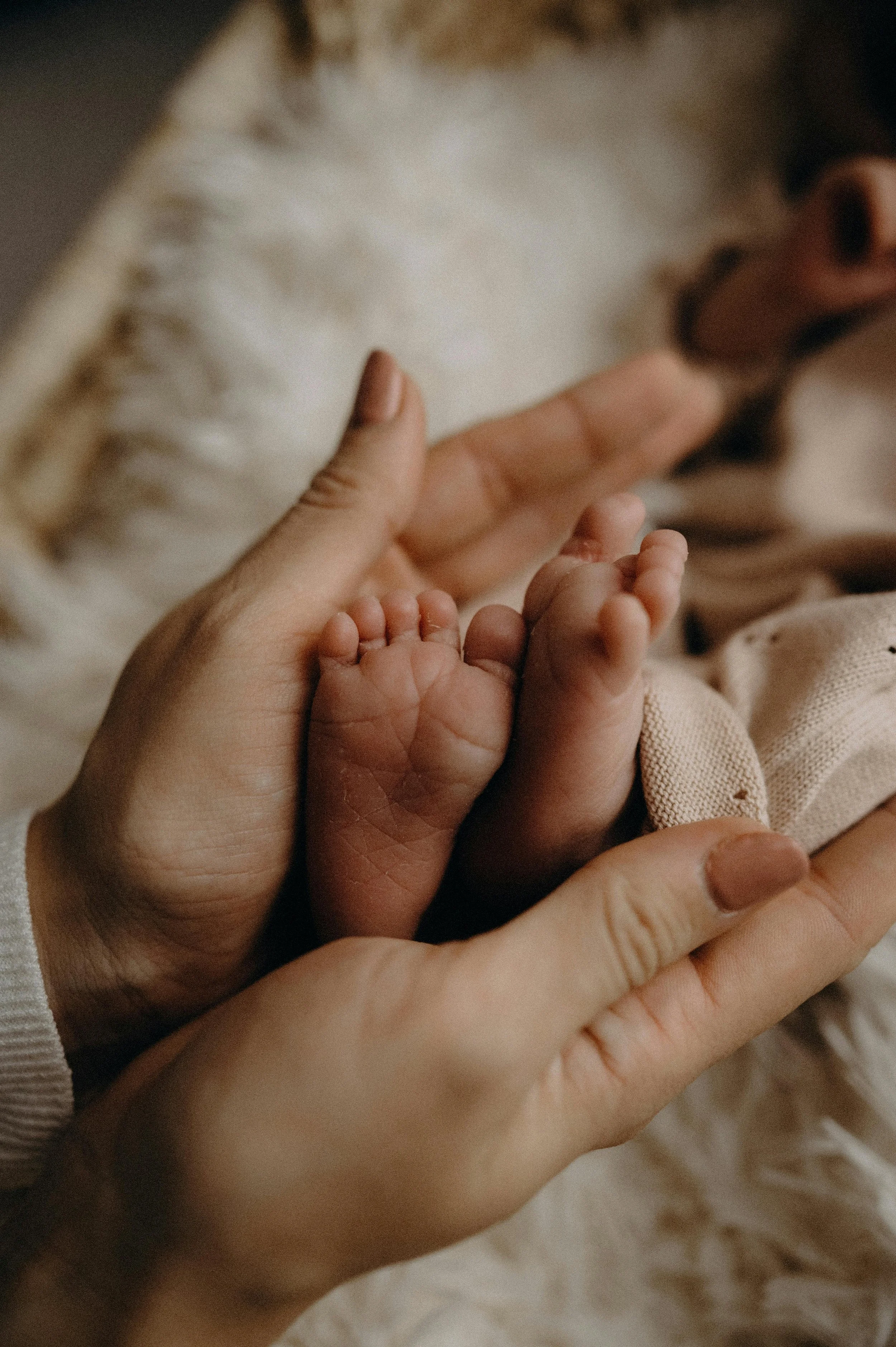 Close-up of an adult's hand gently holding a newborn baby's tiny hand.