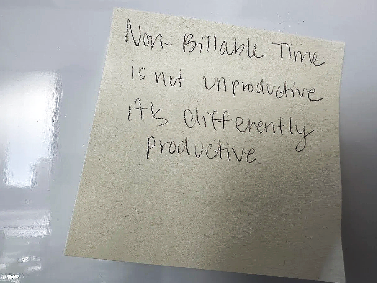 A yellow sticky note with handwritten text that reads, 'Non-billable time is not unproductive. It’s differently productive.'