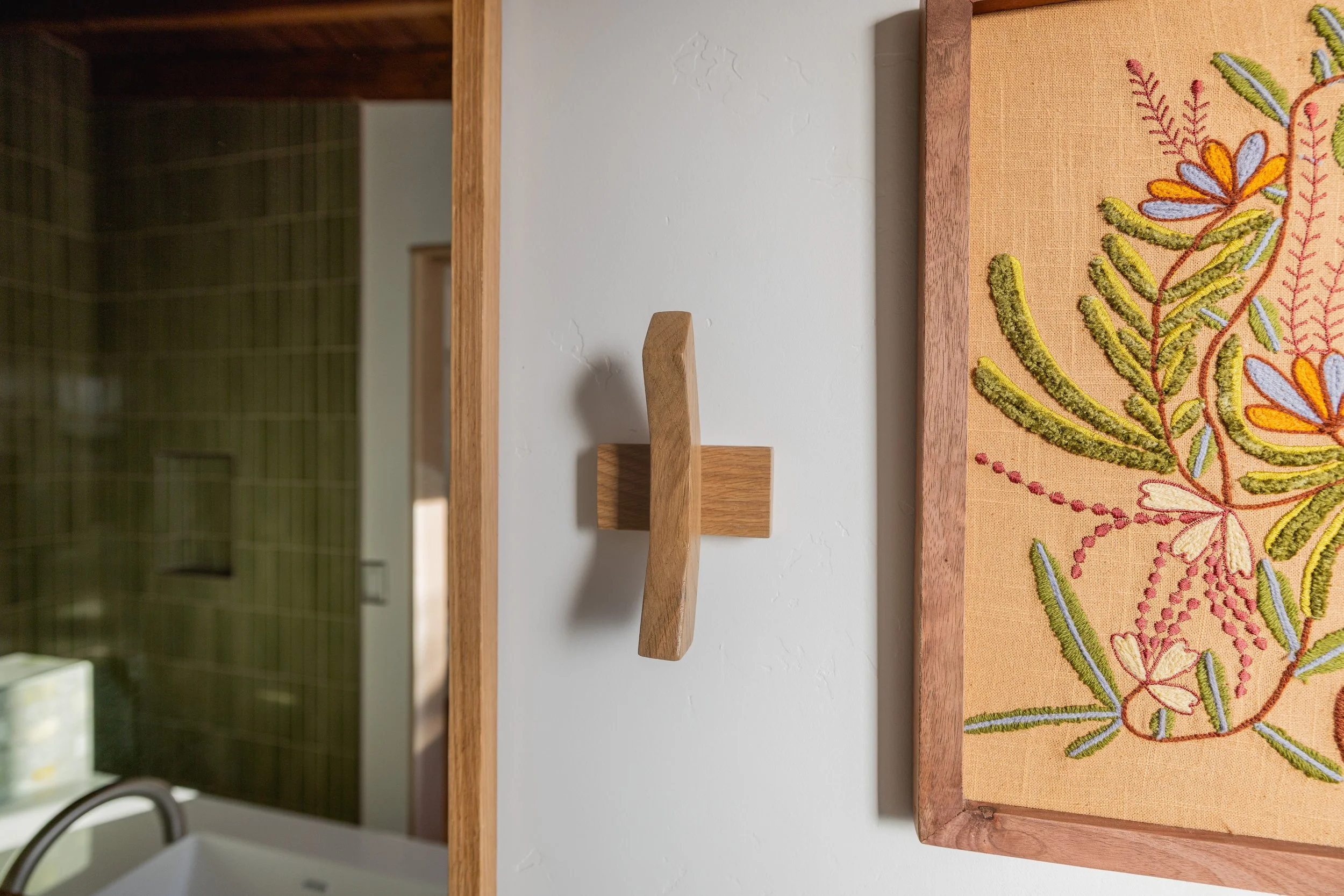 Close up of white oak handmade towel hook and mirror in mid century modern bathroom designed by Geis Architecture