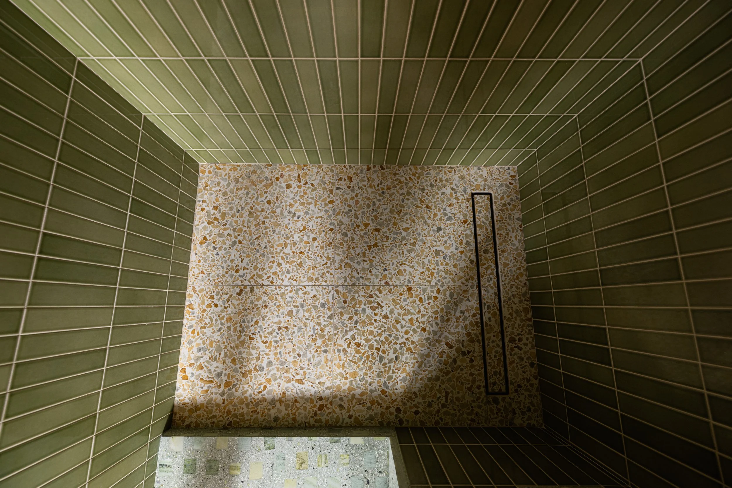 Image of shower floor and lower walls, mid century modern green design with yellow and white accents. Tile by Zia Tile and Concrete Collaborative. Bathroom in San Diego, California designed by Geis Architecture.