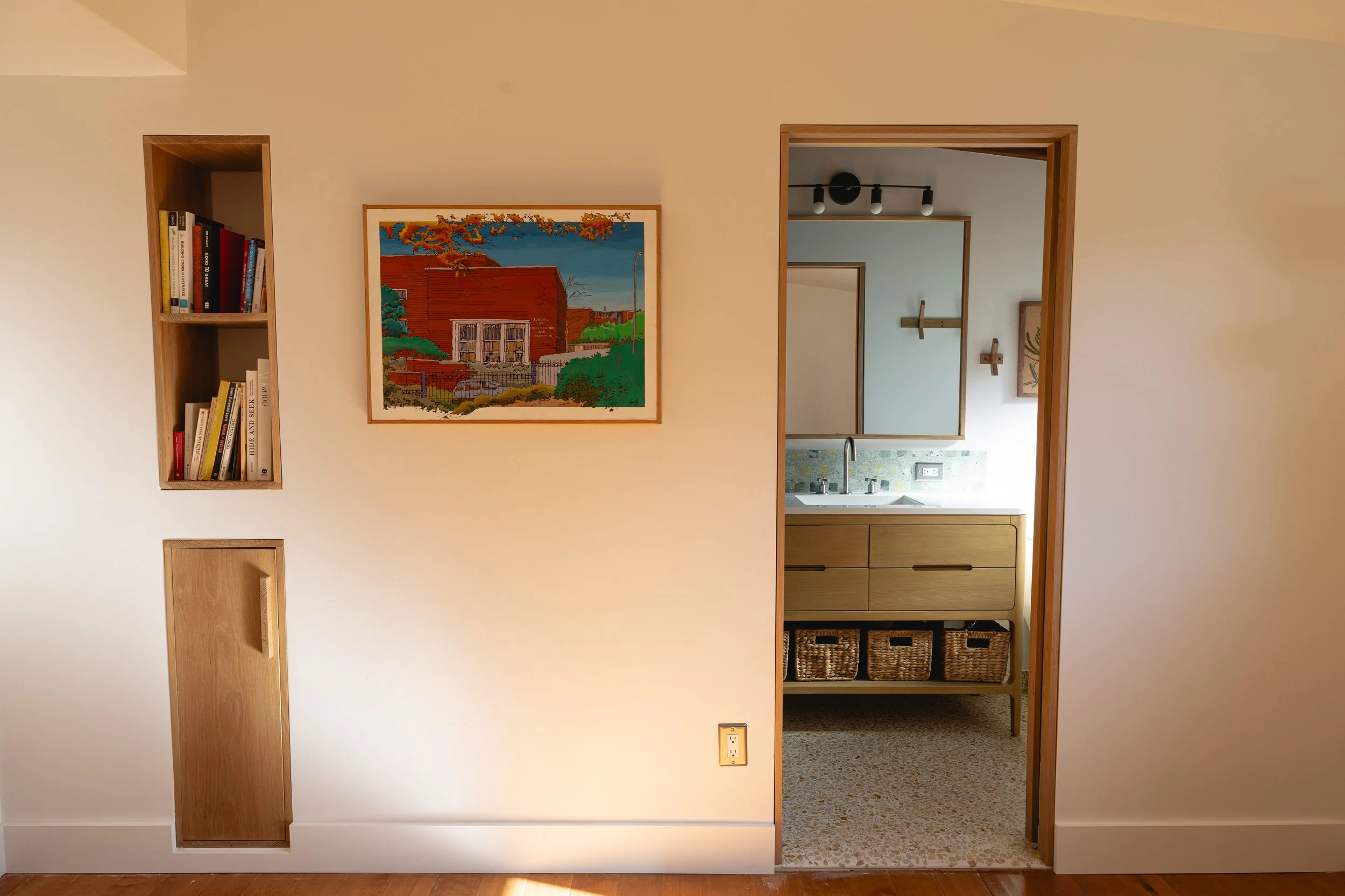 Image looking into the bathroom from the greater room. Art on the wall and niche with architectural books on the shelf. Designed by Geis Architecture in North County San Diego, California. Mid century modern deisgn