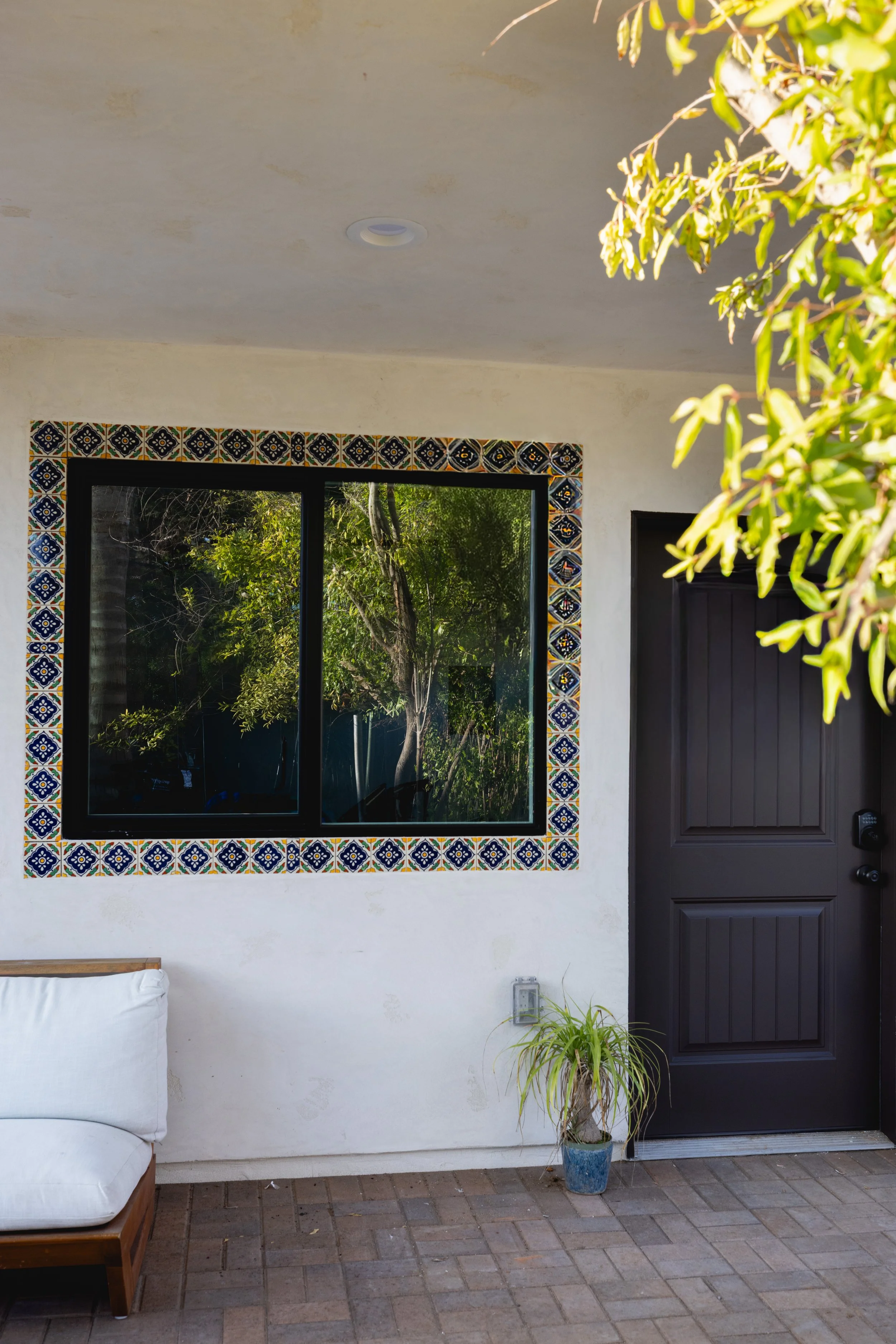 Entrance to new ADU located in Carlsbad, California. Window with Spanish style tile surrounds and pomegranate trees relfecting in the glass. Beautiful, new build designed by Geis Architecture