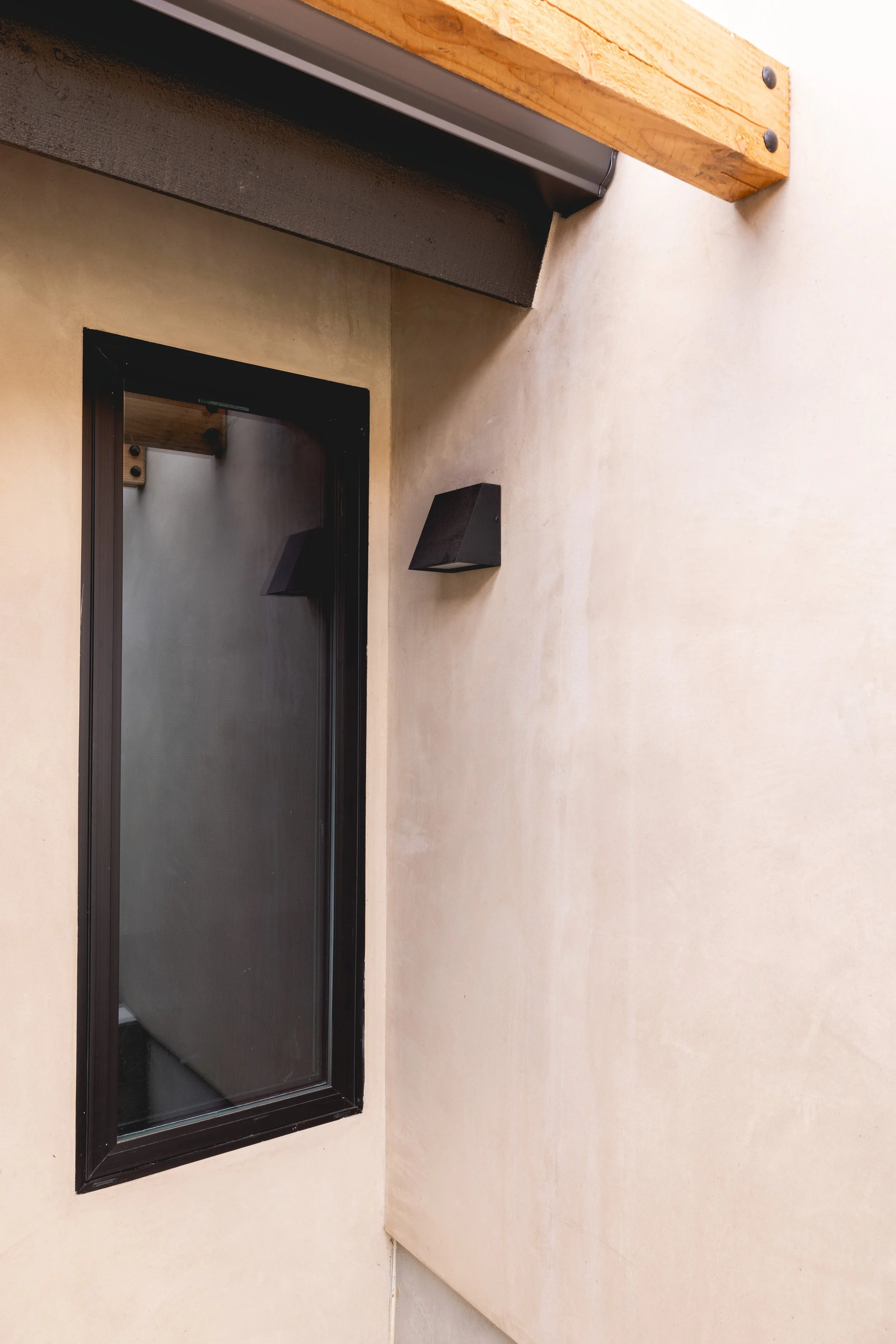 Image of new black modern window and light fixutre on exterior of renovated home by Geis Architecture