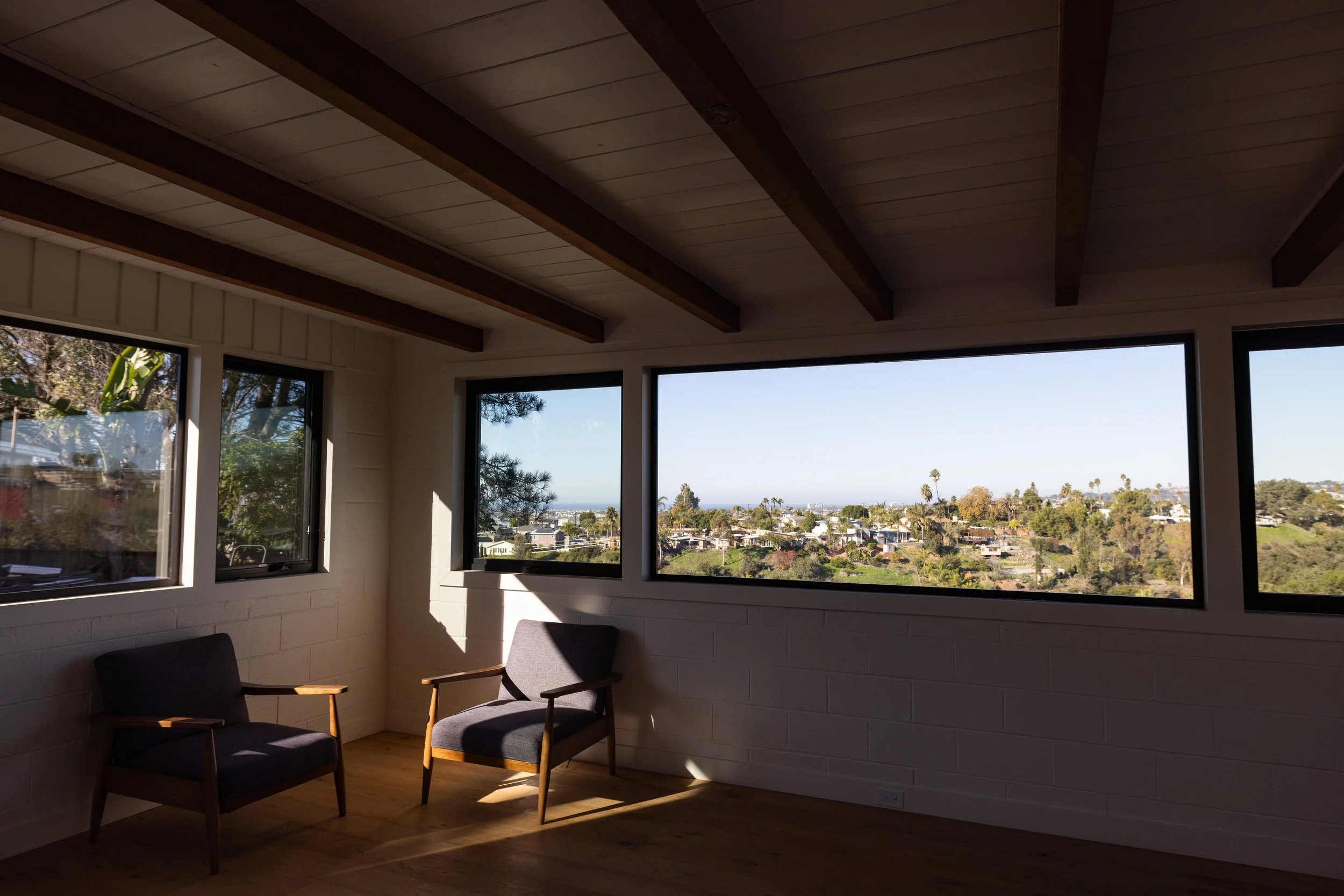 Image of newly remodeled living area by Geis Architecture with sweeping views of the San Diego Bay area, ocean, and palm trees