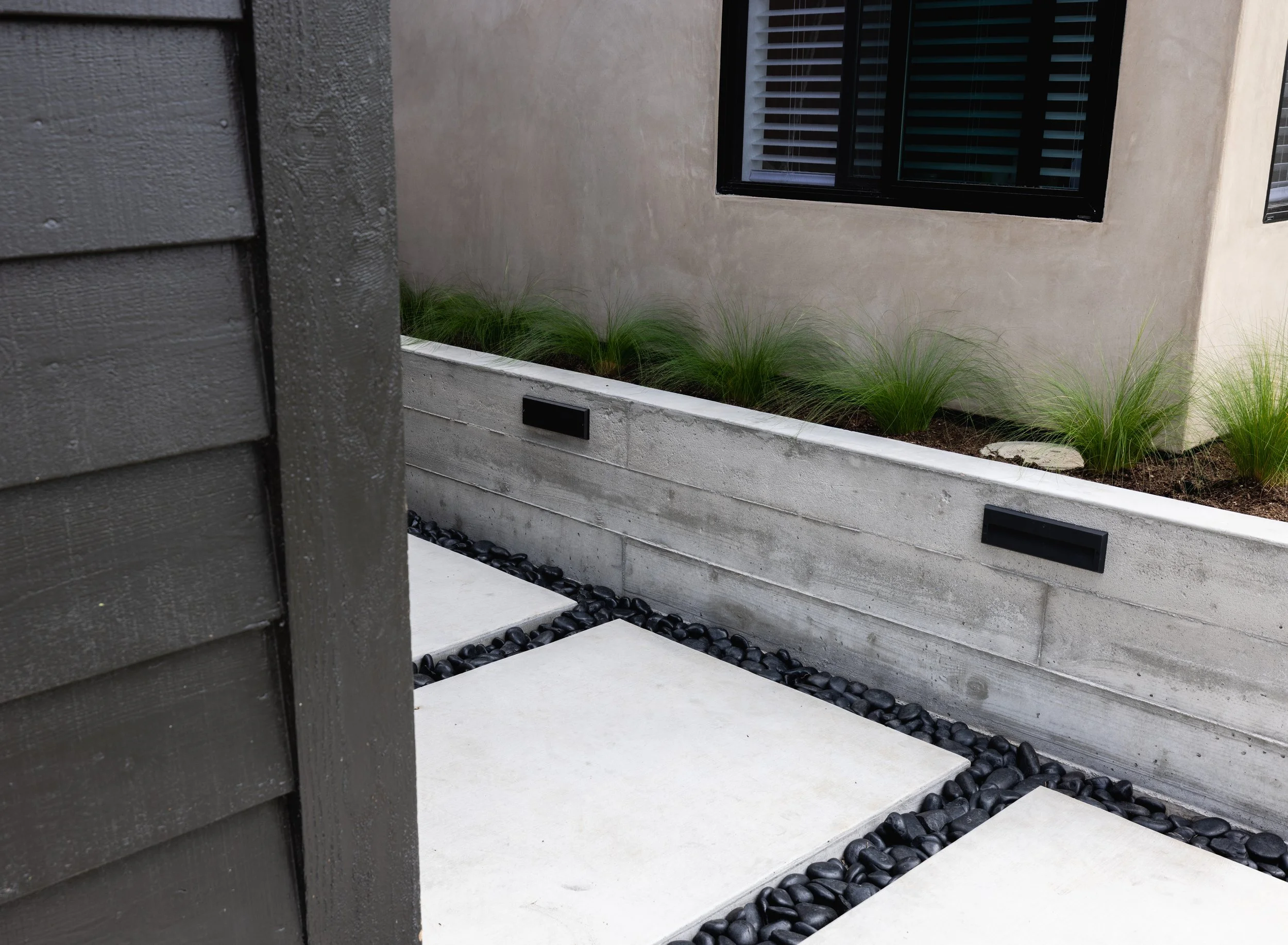 Large concrete pavers with Mexican feather grass in planter above on this newly remodeled Carlsbad home