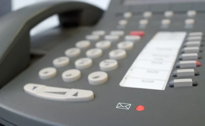 Close-up of a conference phone with buttons, a red indicator light, and a small envelope icon.