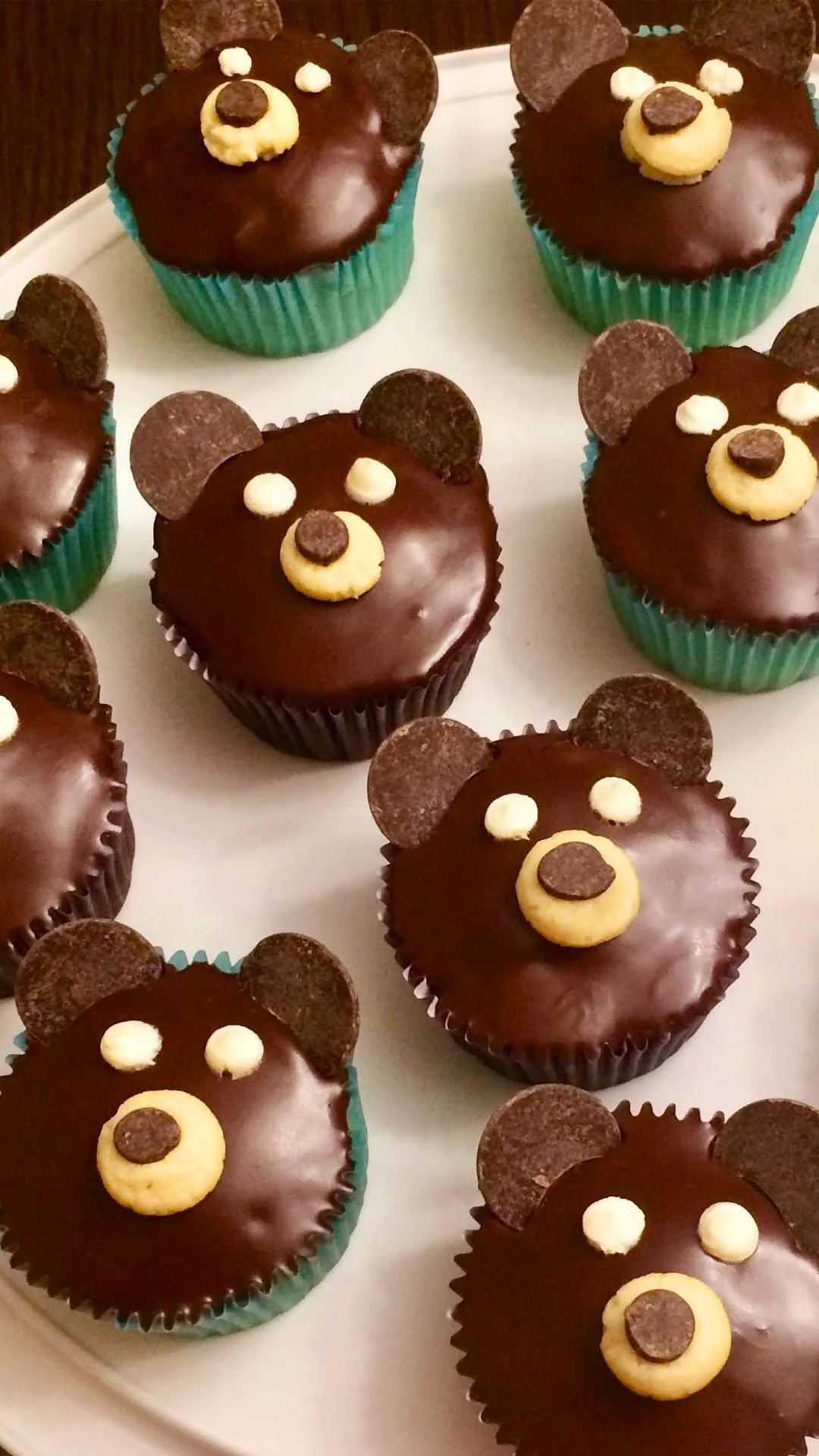 Cupcakes decorated to look like bear faces with chocolate and cream accents.