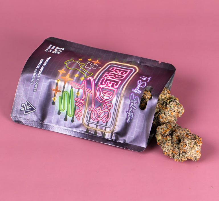 A bag with neon signs and star graphics, opened with cannabis buds partially visible on a pink background.