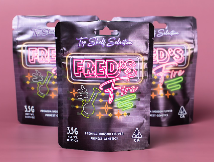 Three packs of Fred's Fire indoor flower cannabis product with neon-style packaging, purple background, and a flame icon.