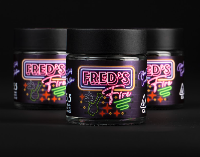 Three small jars of a cannabis product labeled 'Fred's Fire' with neon-style graphics, set against a black background.