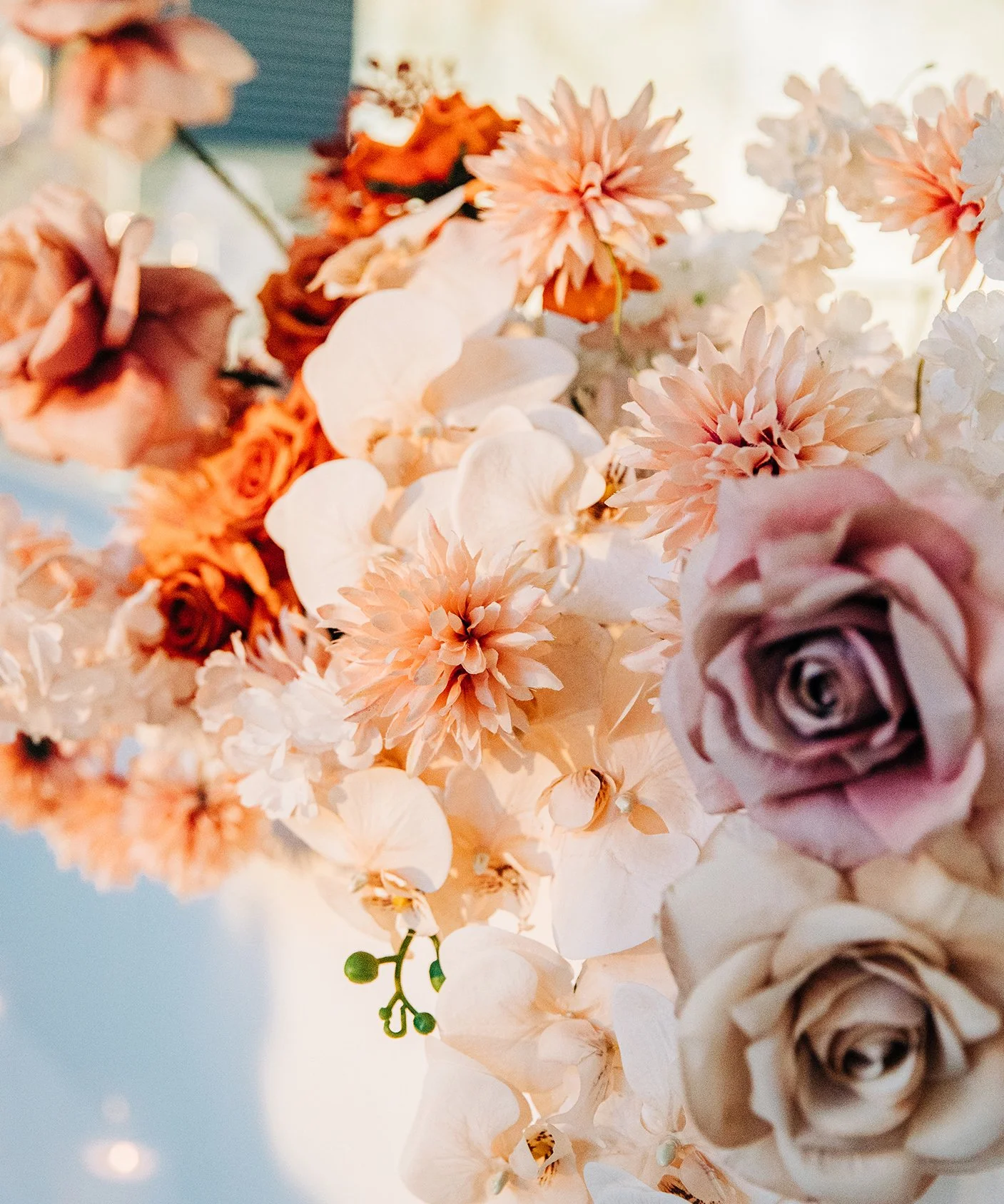 Close-up of a bouquet of pastel-colored roses, dahlias, orchids, and other flowers.