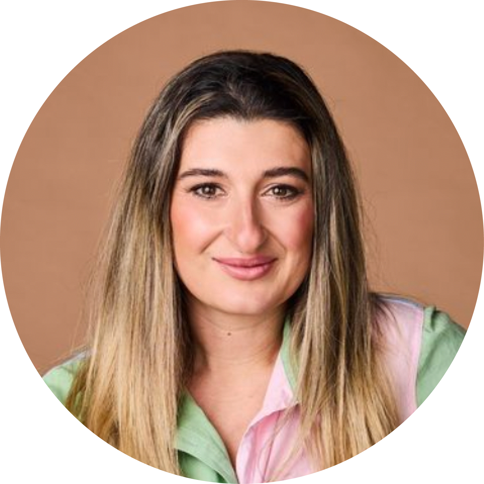 Portrait of a woman with long hair, smiling, wearing a pastel green and pink top, against a beige background.